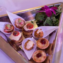 Assorted canapés on a mirrored tray with an orchid