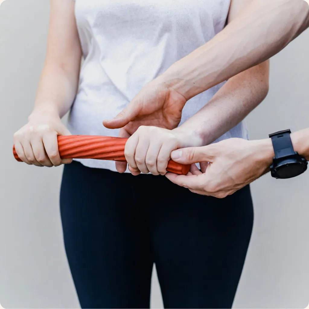 Handübung mit einem roten Trainingsstab