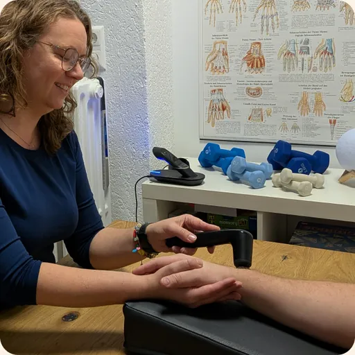 Therapeutin behandelt die Hand einer Patientin am Behandlungstisch