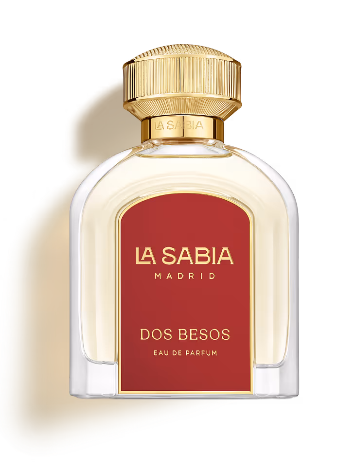 Clear perfume bottle with gold cap and red label reading La Sabia Madrid Dos Besos Eau de Parfum.