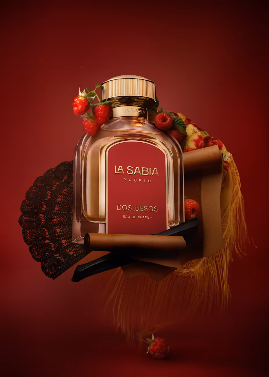 La Sabia Madrid Dos Besos perfume bottle surrounded by raspberries, black lace, and yellow fringe textile.