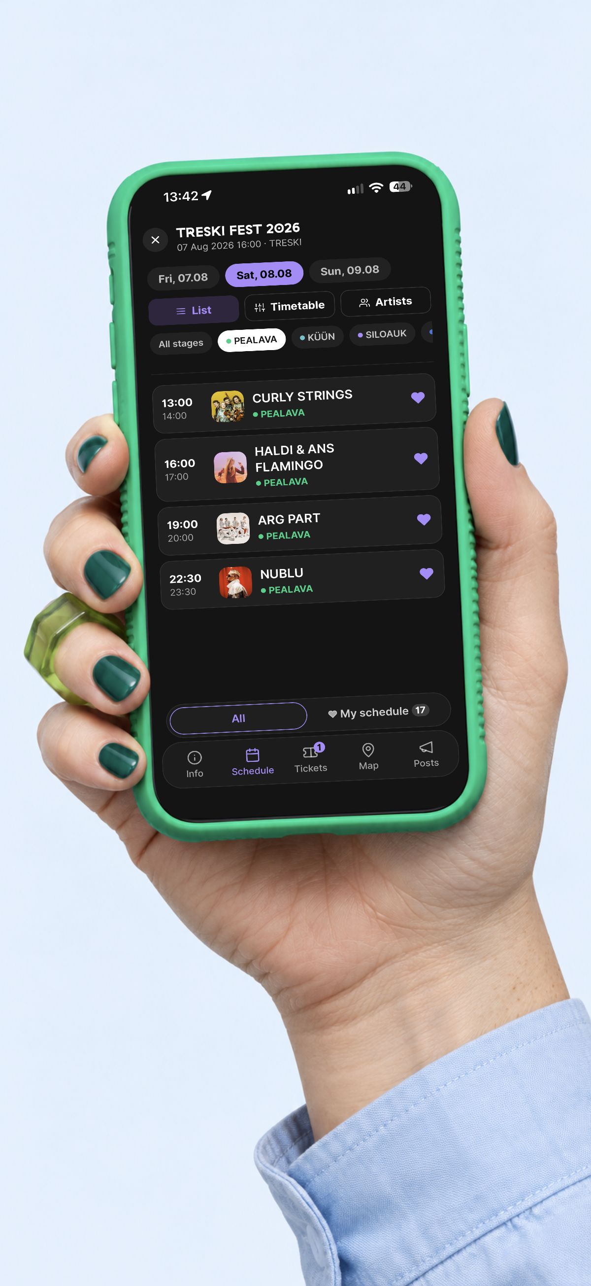 A broad fair hand with short green nails and a translucent green ring holds the original Sviby schedule in a green phone case on a light blue background