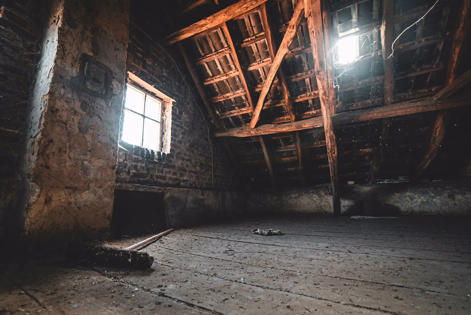 Unfinished attic with rafters and a gable window in a Northern New Jersey home