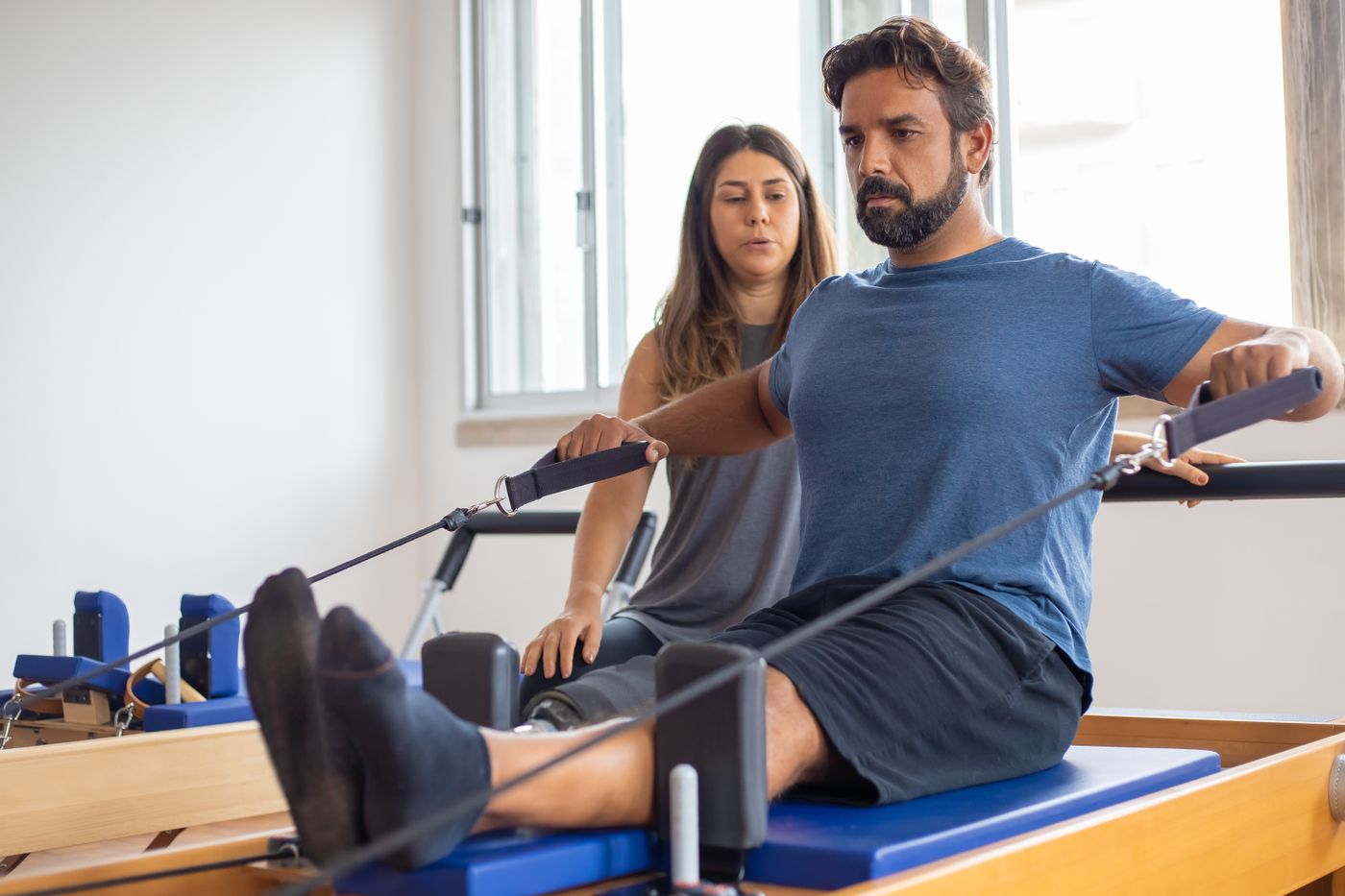 An older member mid-session, trainer guiding the movement