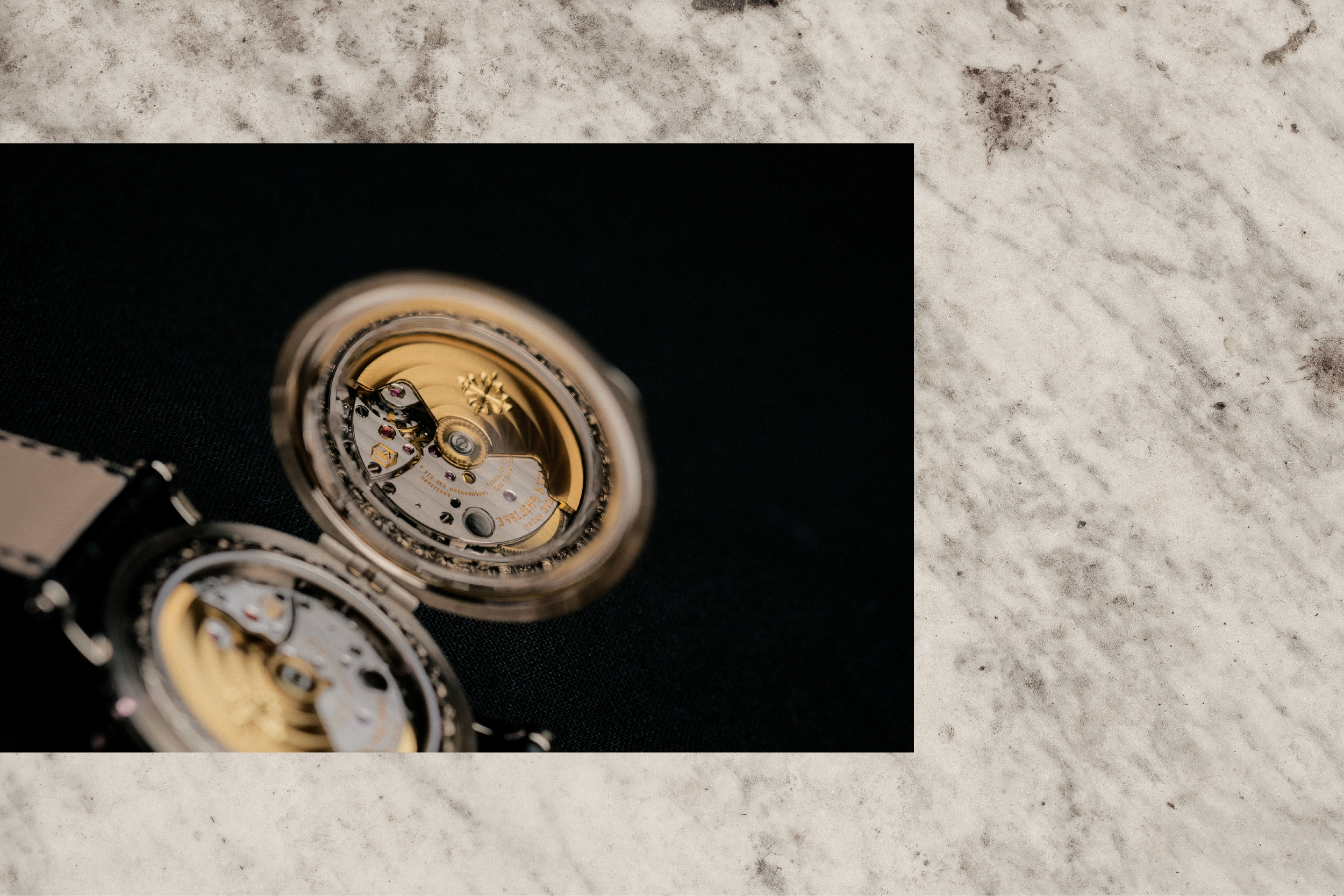 An open pocket watch resting on marble