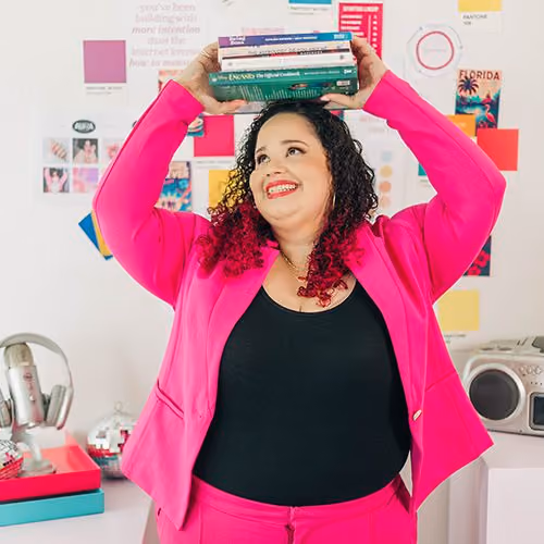 Kristine Gonzalez playfully balances a stack of marketing and business books on her head.