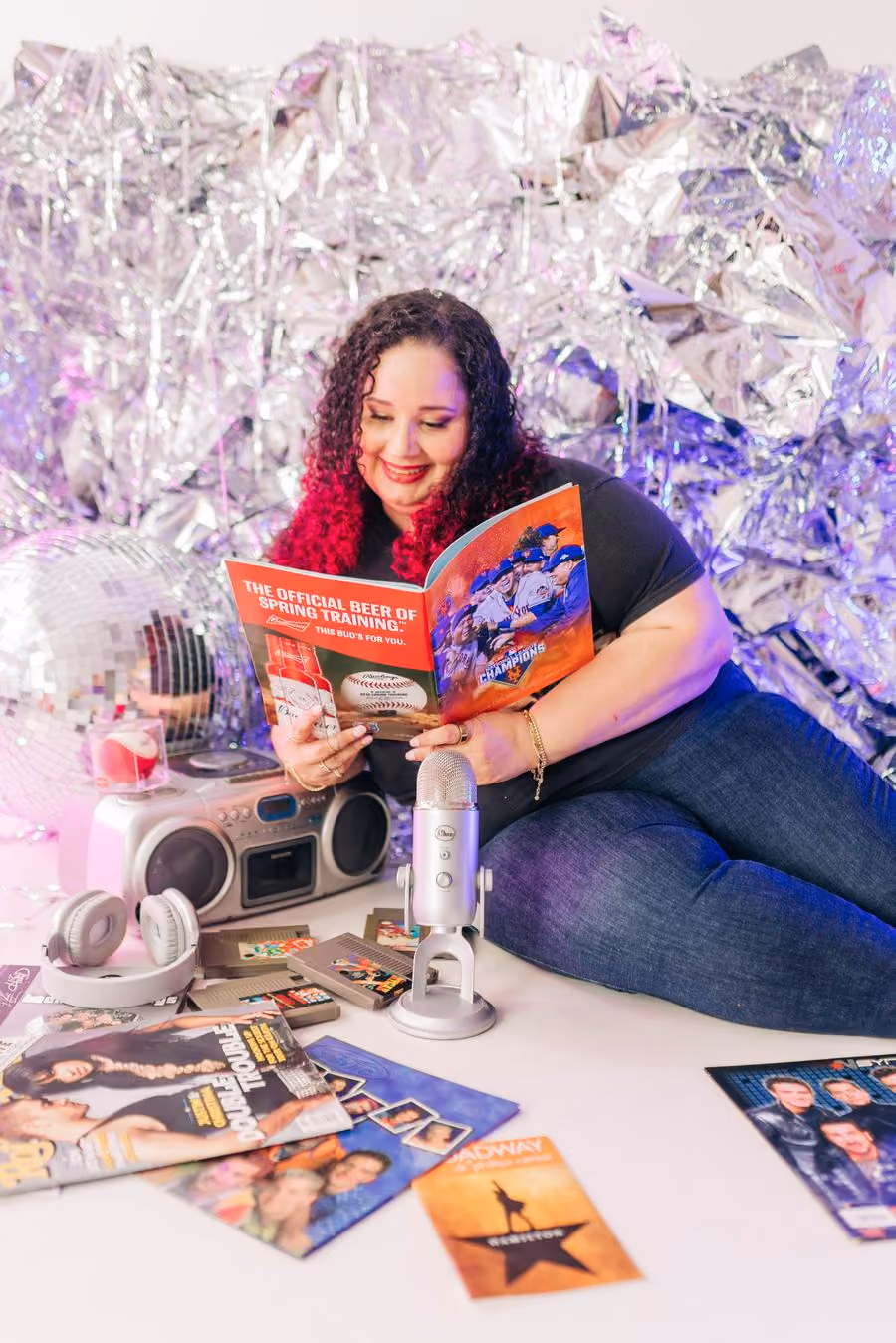 Kristine Gonzalez sitting among records and magazines in front of silver tinsel