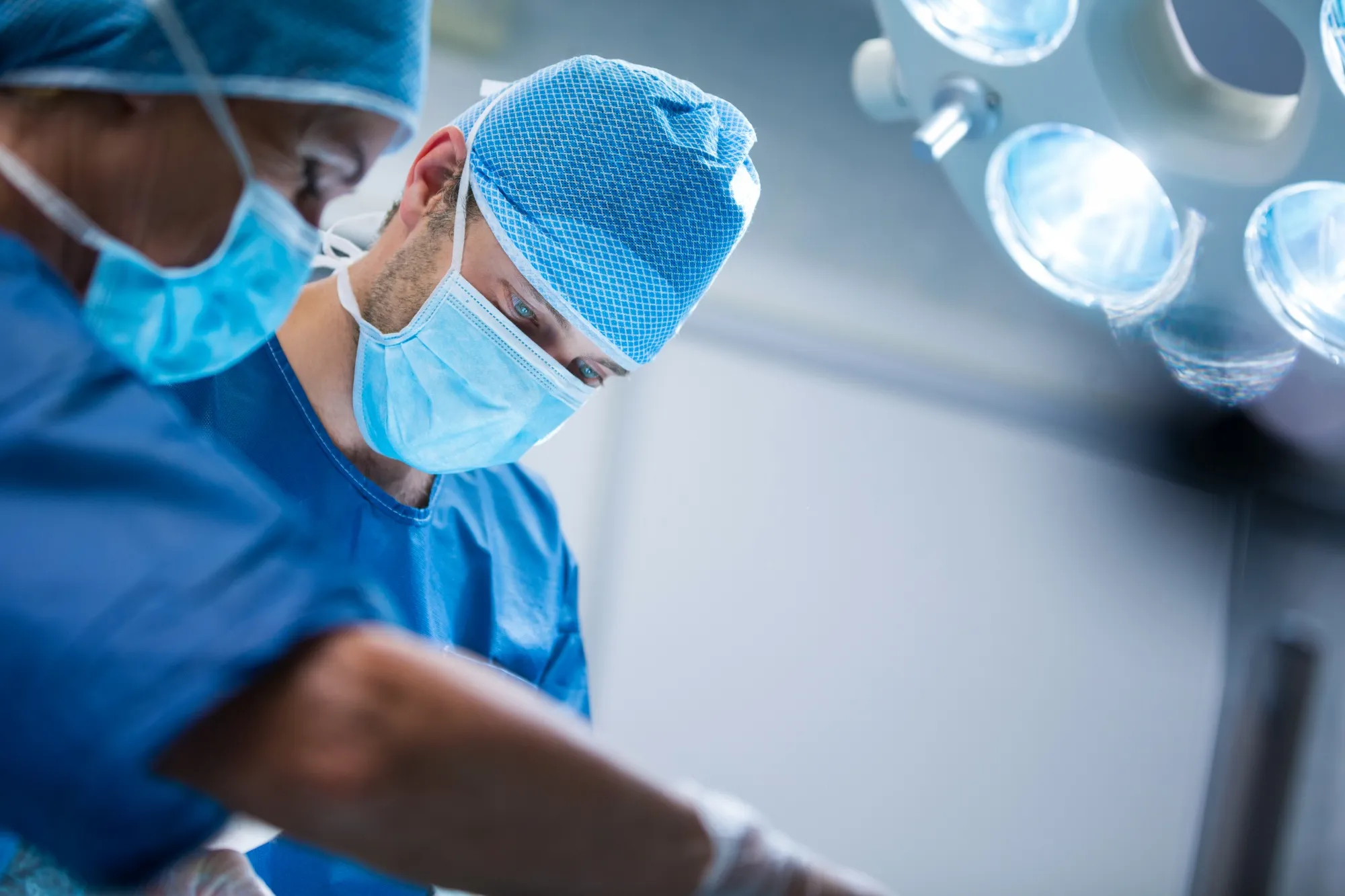 Cirujano y personal médico en quirófano durante un procedimiento, bajo luces de cirugía