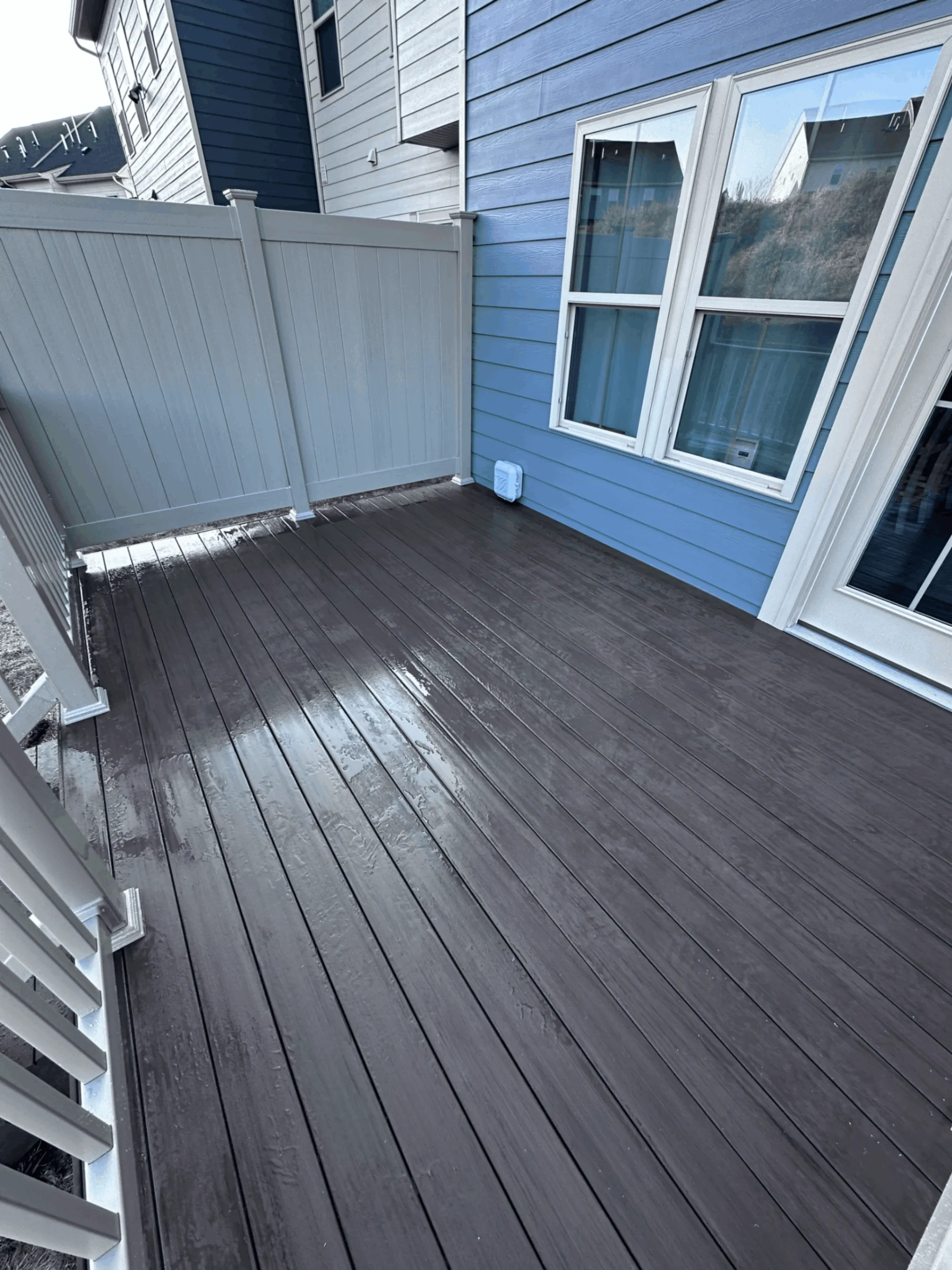 Gray composite deck with a privacy screen panel against blue siding