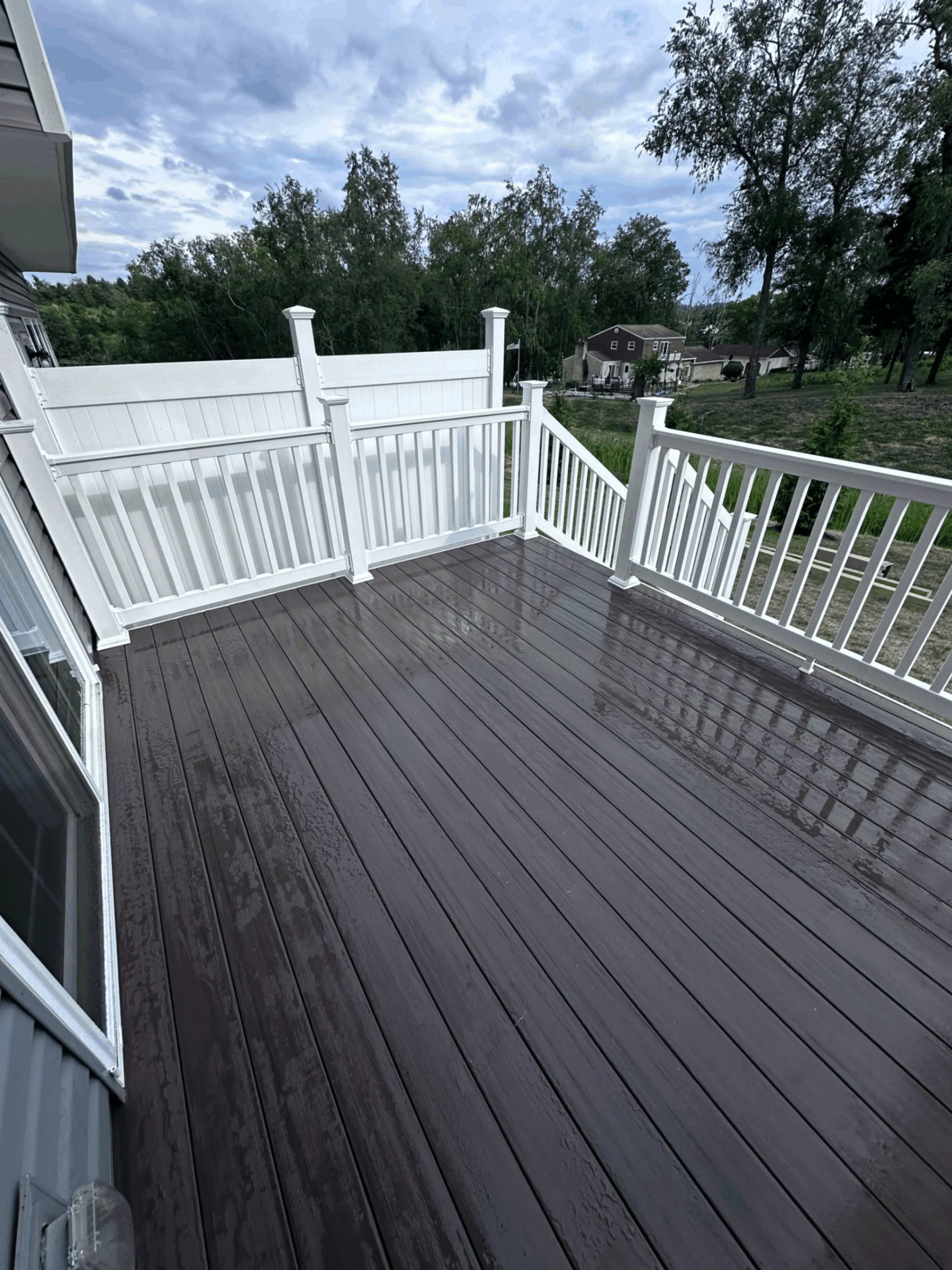 Dark brown composite deck with white vinyl railings overlooking trees