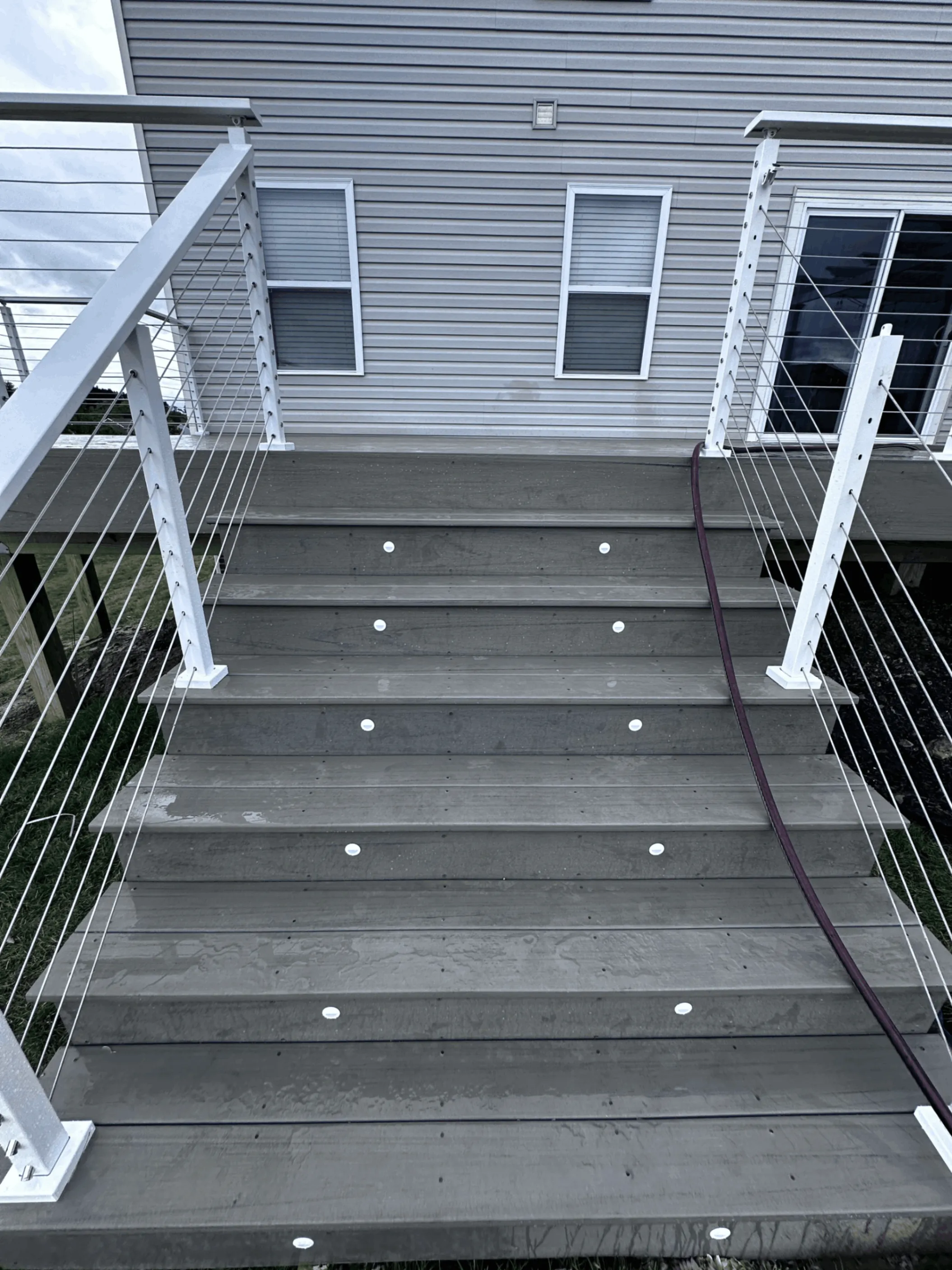 Gray deck stairs with recessed riser lighting and white cable railing