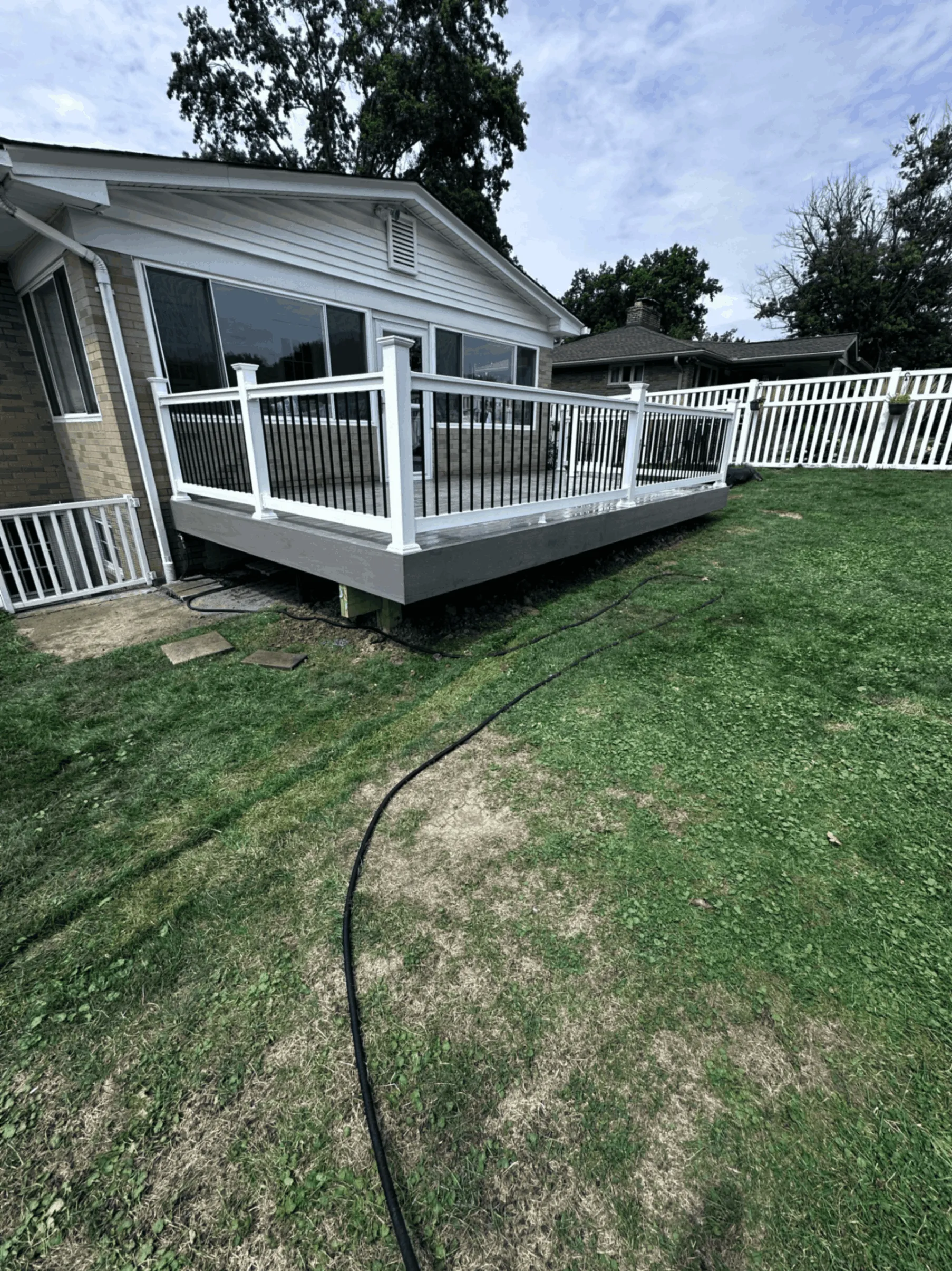 White deck railings with black balusters beside an enclosed sunroom