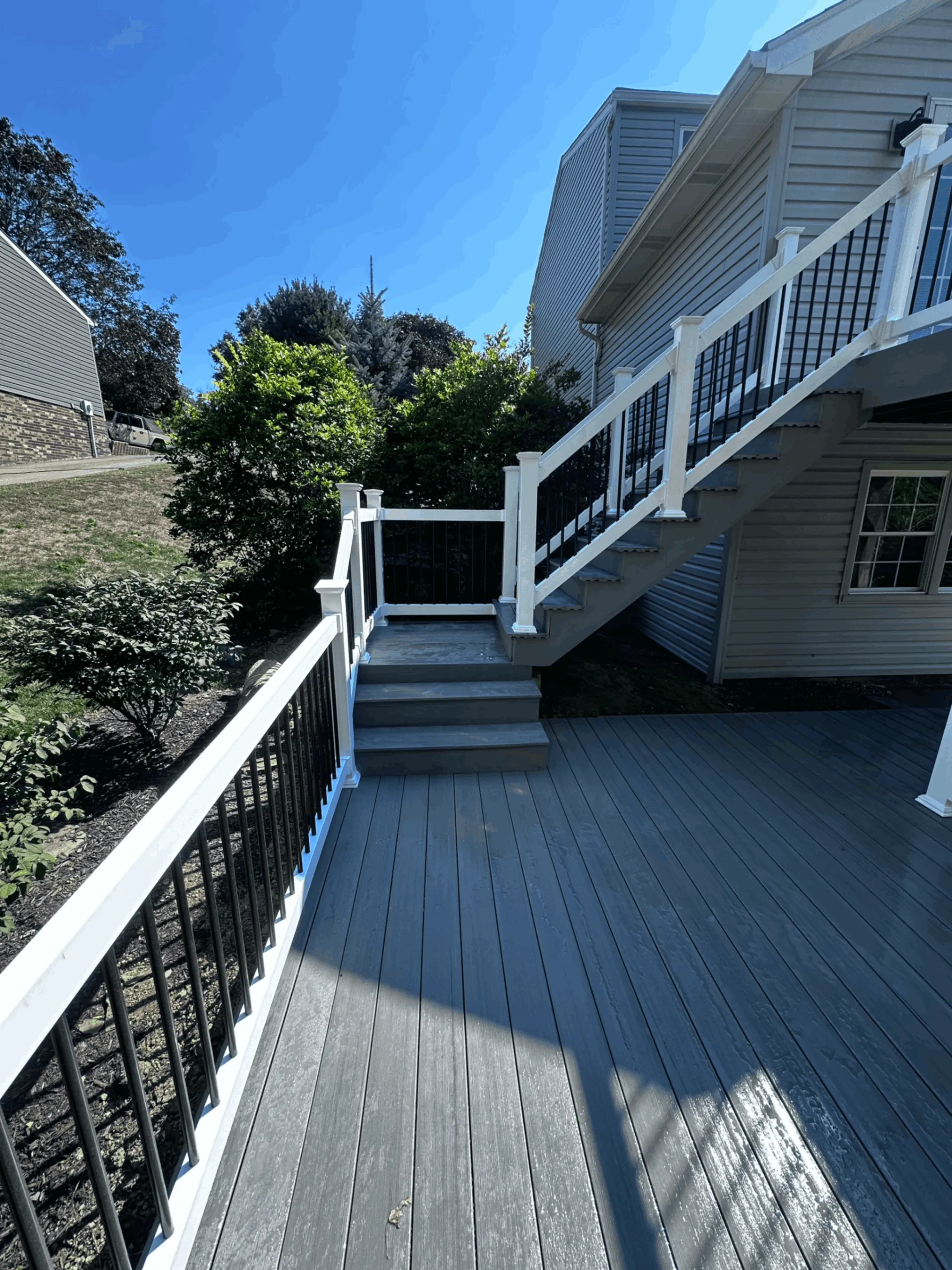 Gray composite deck and stairs beside a home with a stone chimney