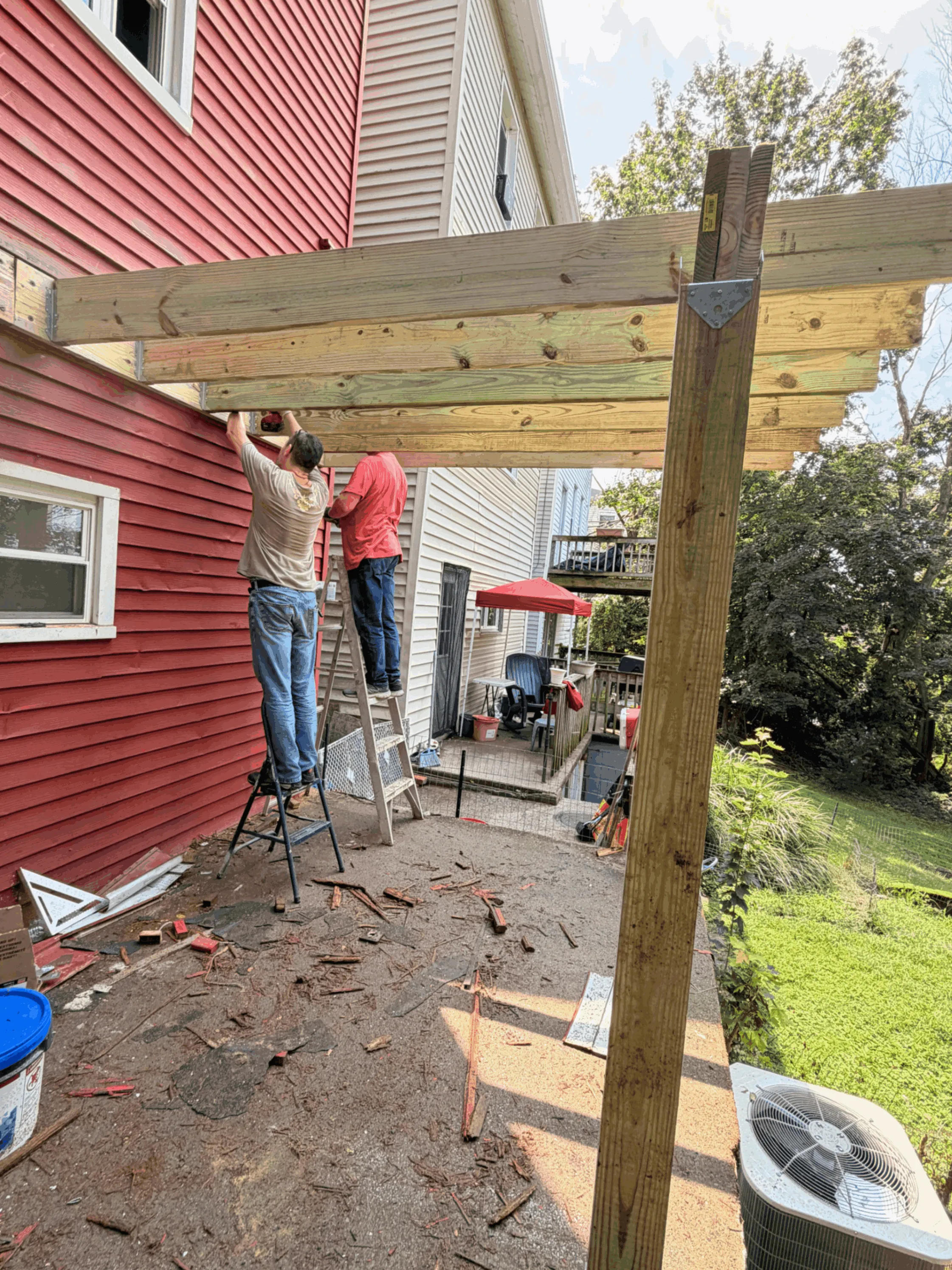 Crew installing overhead beams for a covered deck frame during construction