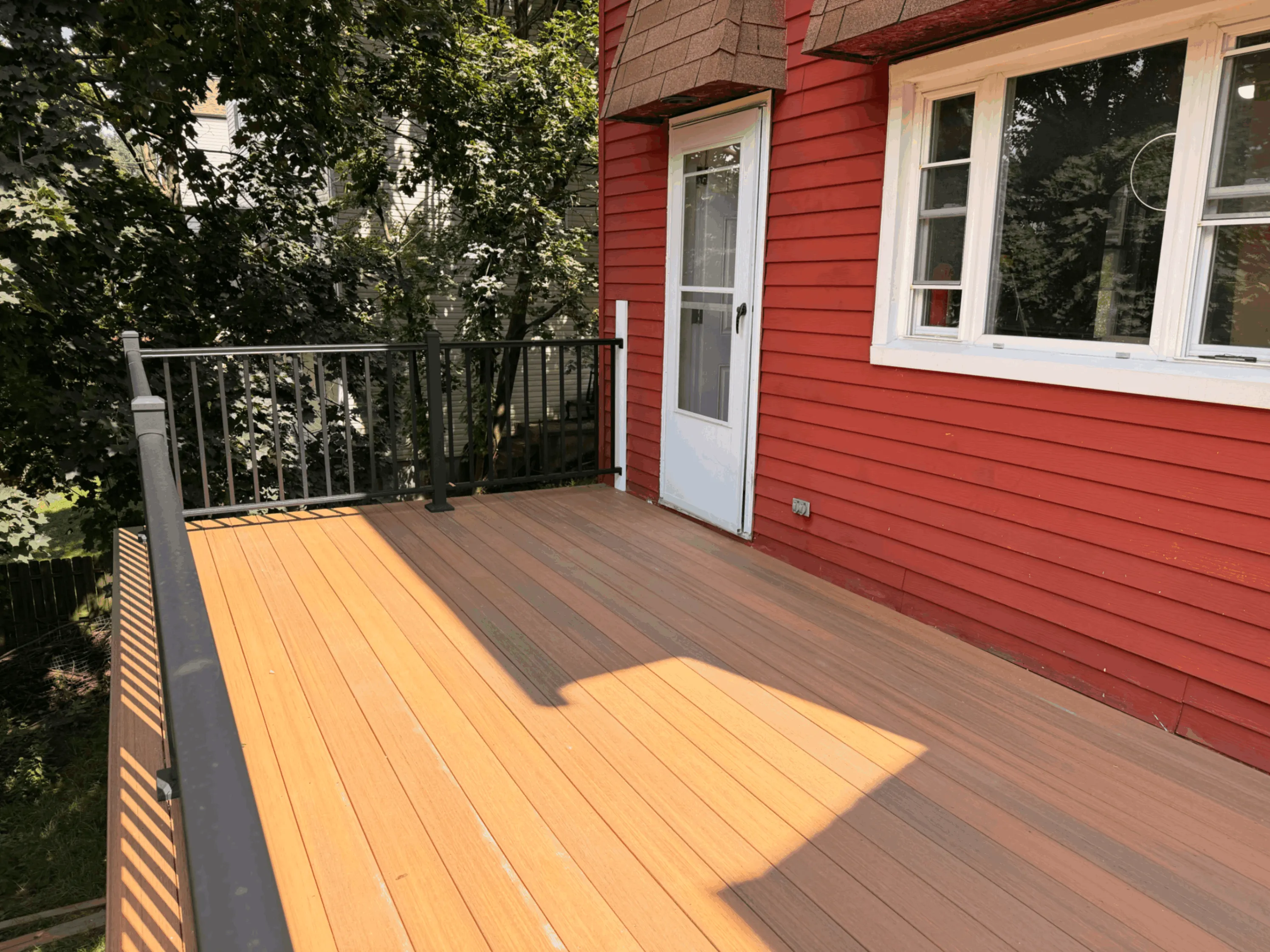 Composite deck with contrasting border boards outside a red sided home