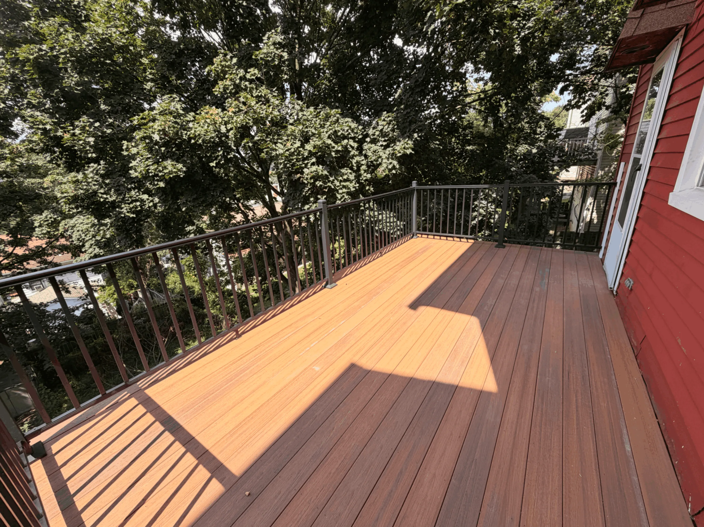 Two-tone composite deck with black railings surrounded by mature trees