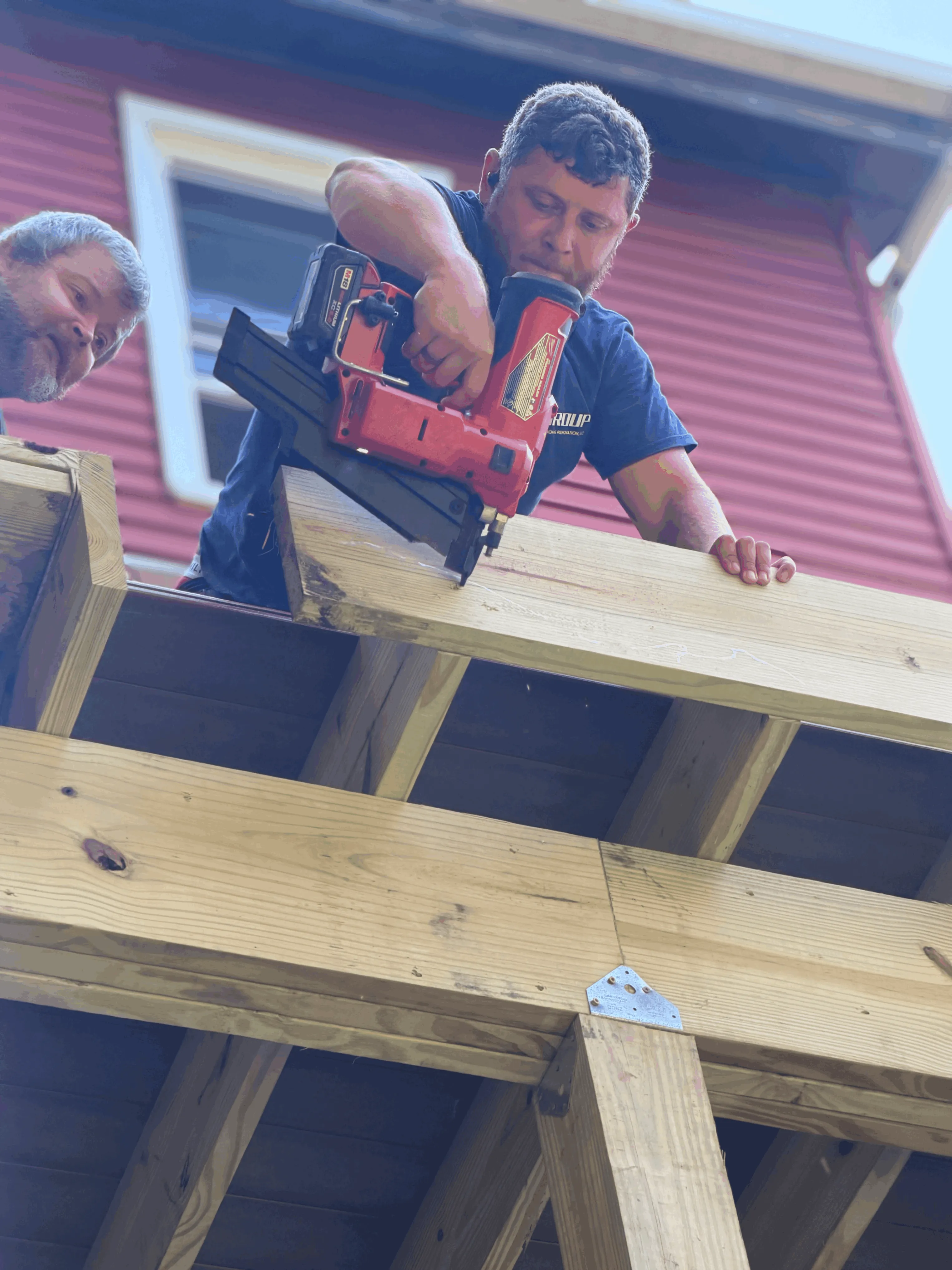 Crew members fastening deck framing with a nail gun during construction