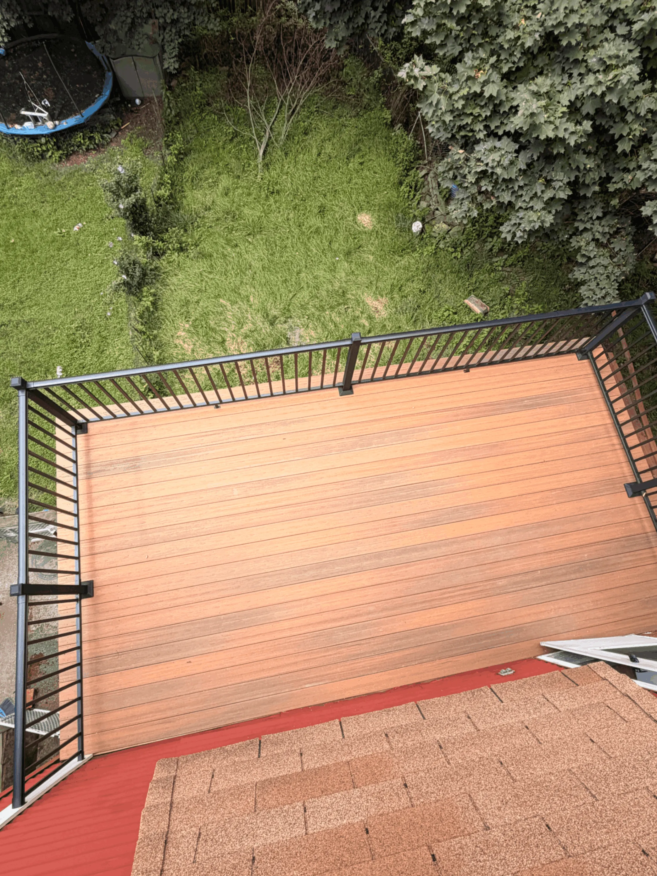 Overhead view of a light composite deck with black railings beside a lawn
