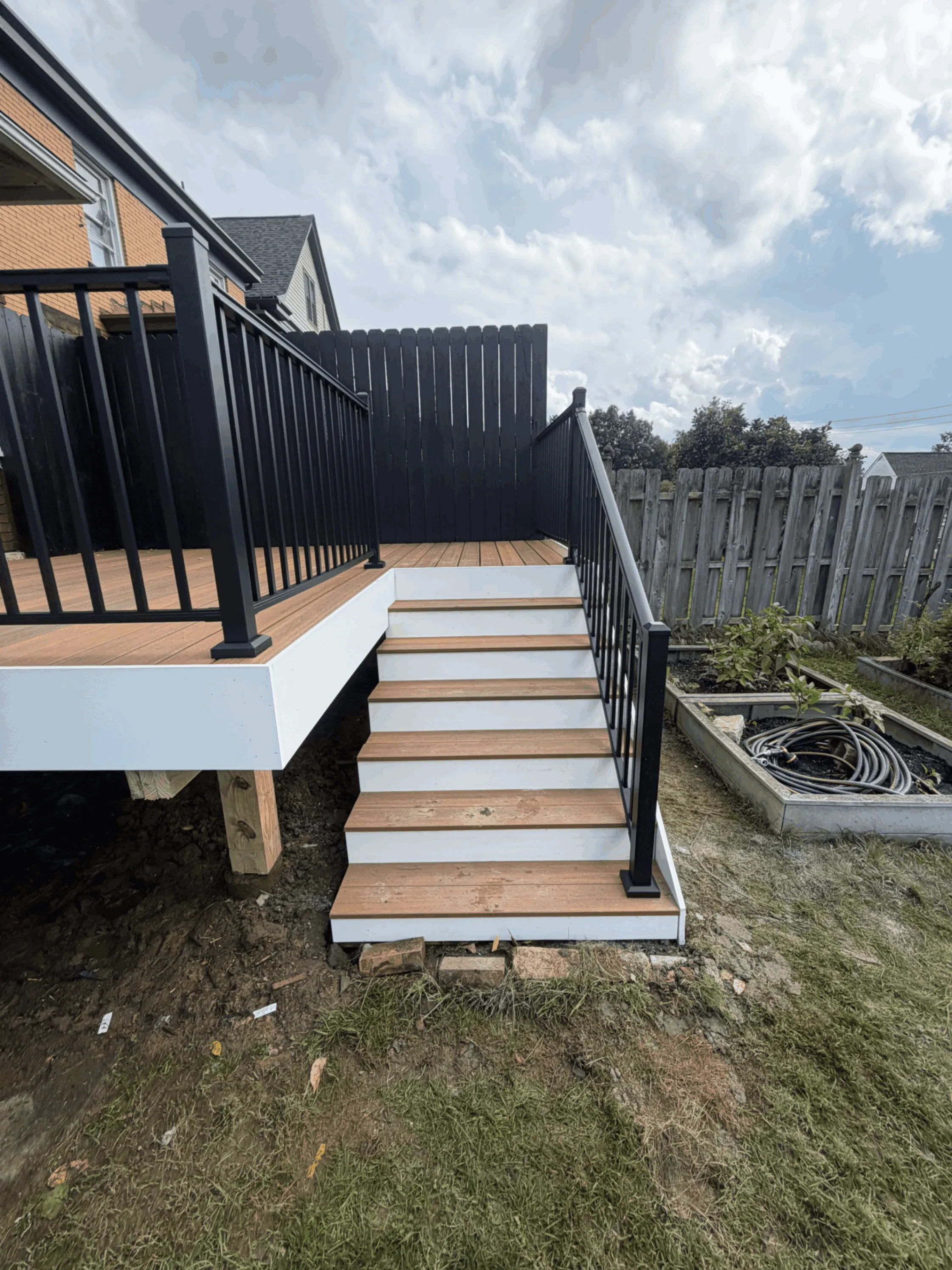 Deck stairs with white risers, black railings, and a black privacy screen panel