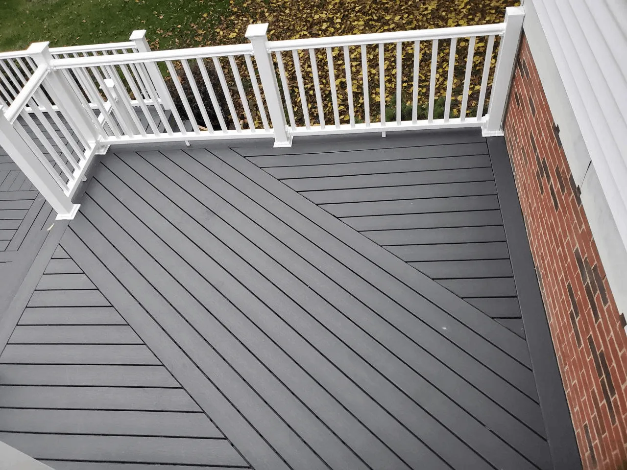 Dark gray composite decking laid in a diagonal pattern with white railings