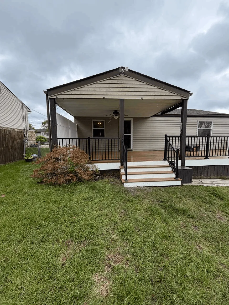 Covered front porch with black aluminum railings and light entry steps on a ranch home