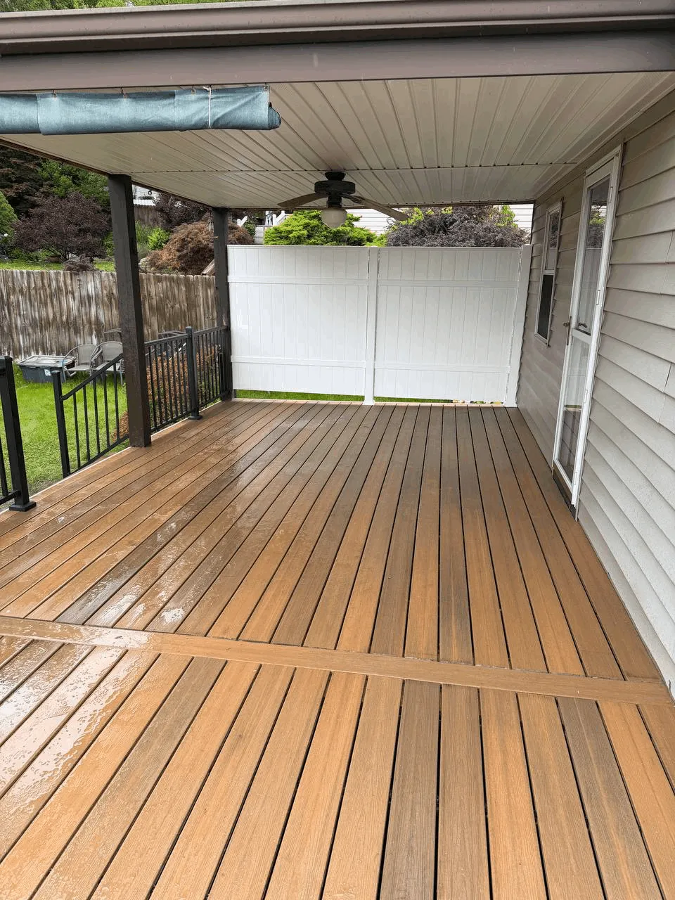 Covered deck with brown composite boards in a diagonal pattern and black railings