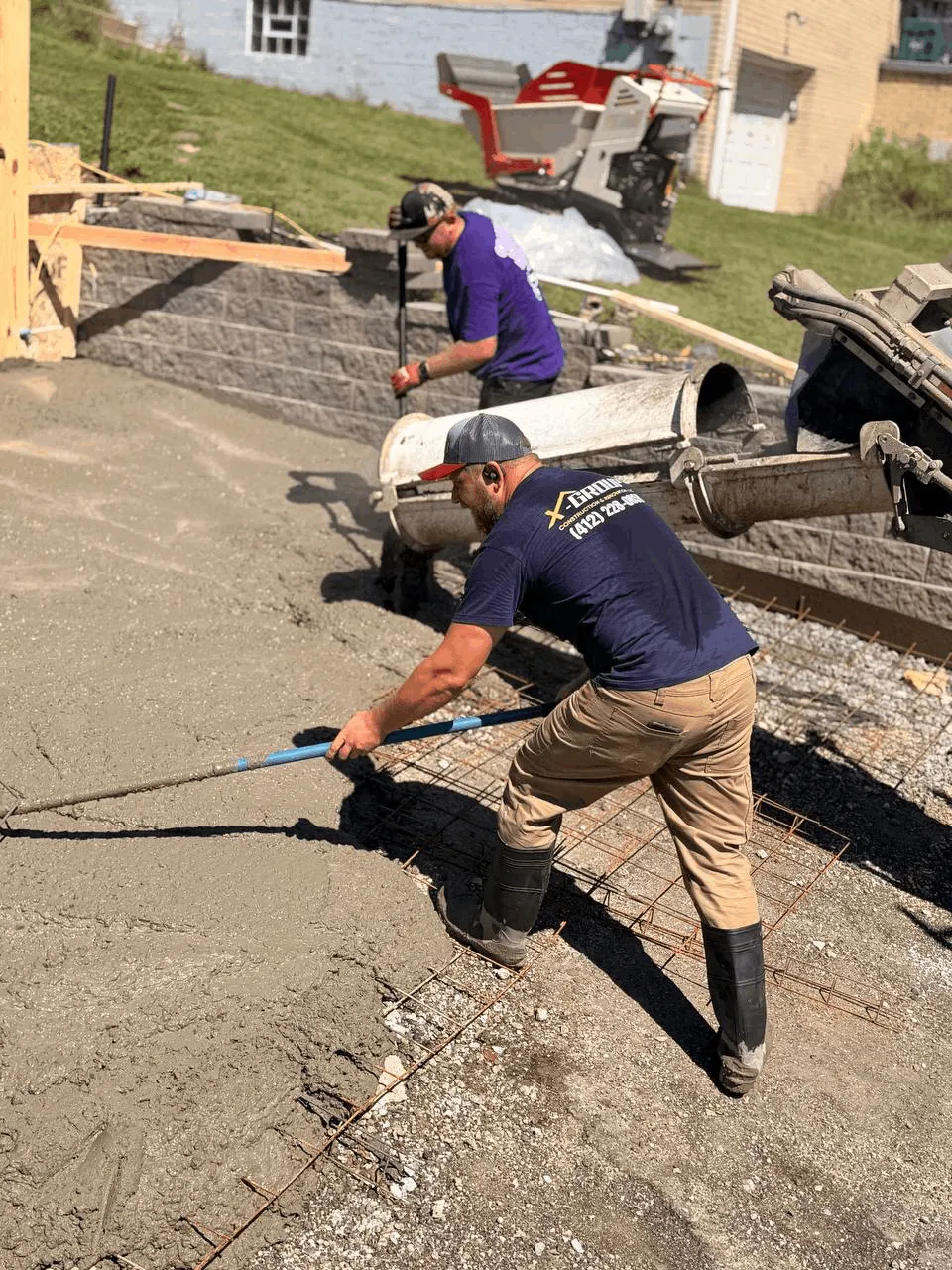 Worker screeding concrete as it is placed from the mixer truck chute