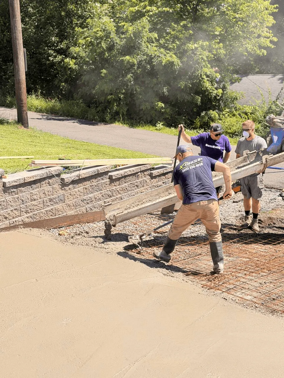 Crew placing and leveling fresh concrete over rebar mesh reinforcement
