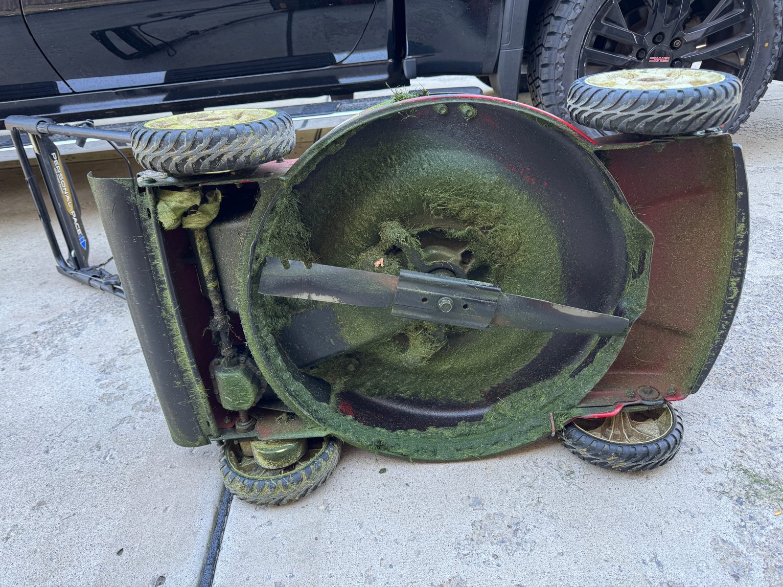 Walking mower deck caked with grass before cleaning