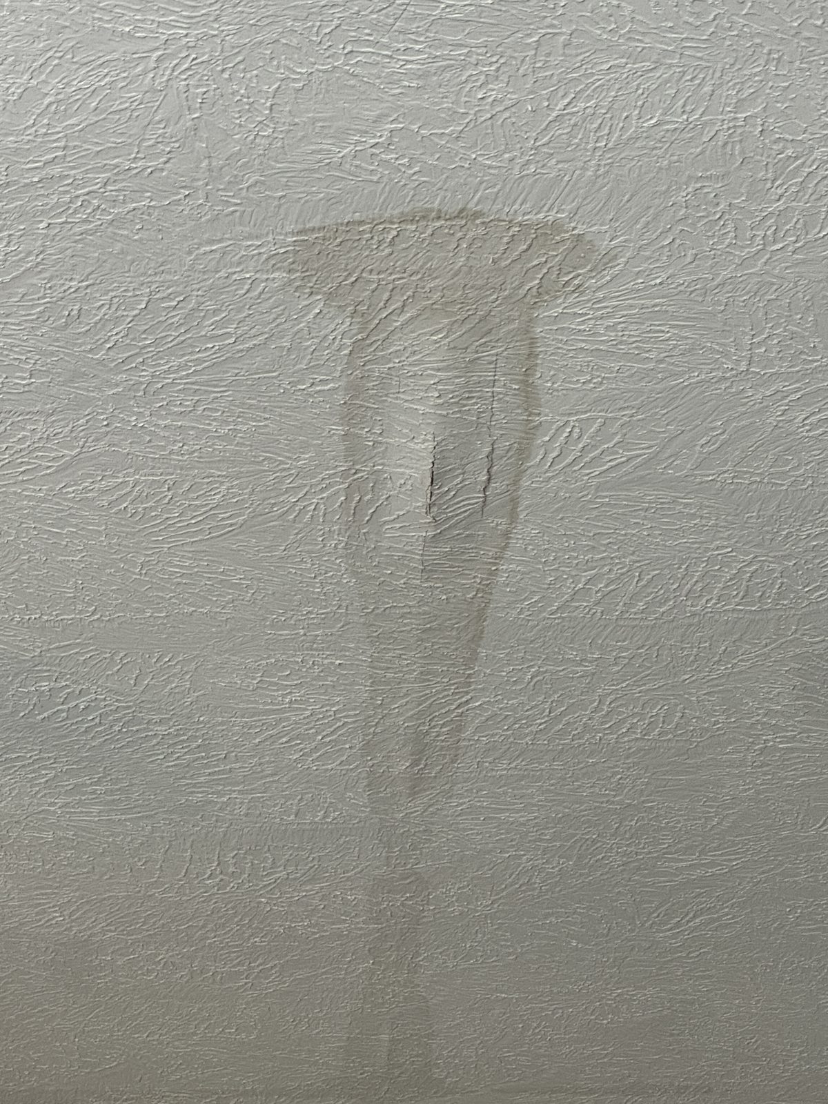 Water stain on a textured bedroom ceiling before the repair
