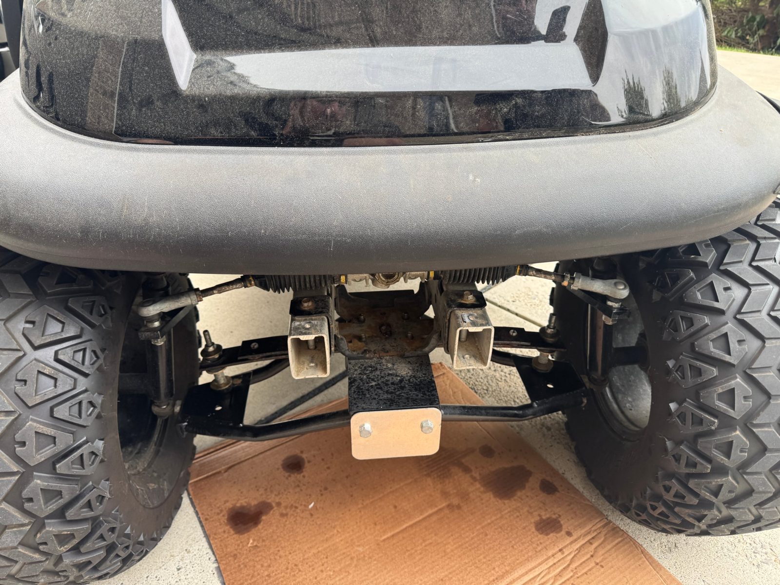 Front of a lifted golf cart with the steering rack and front axle visible after alignment