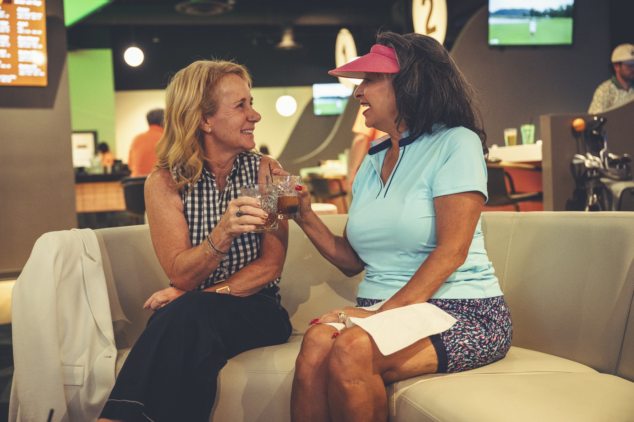 Two friends laughing over cocktails in the lounge area at The PAR Club