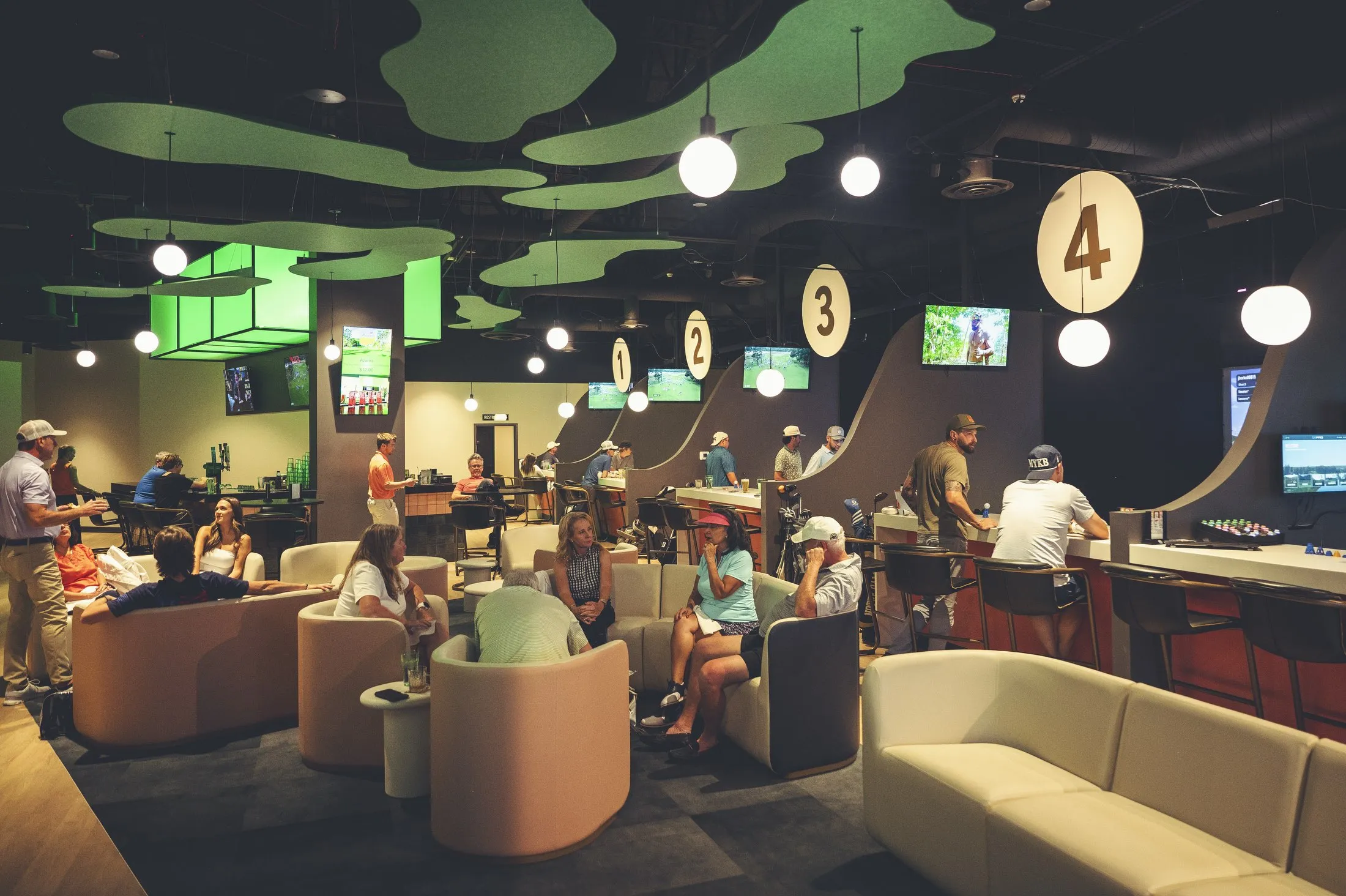 The PAR Club lounge seating with golf simulator bays and guests socializing in Castle Rock