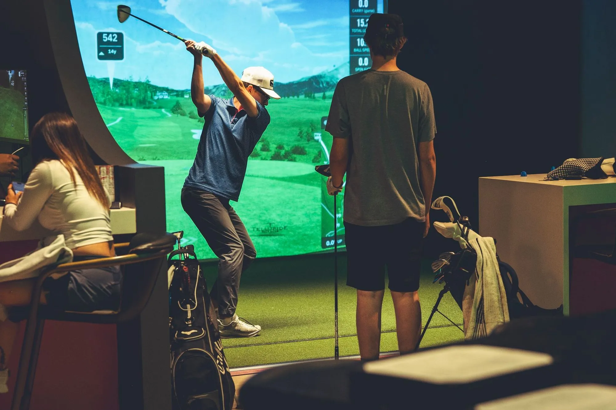 Golfer taking a swing on a simulator screen at The PAR Club in Castle Rock