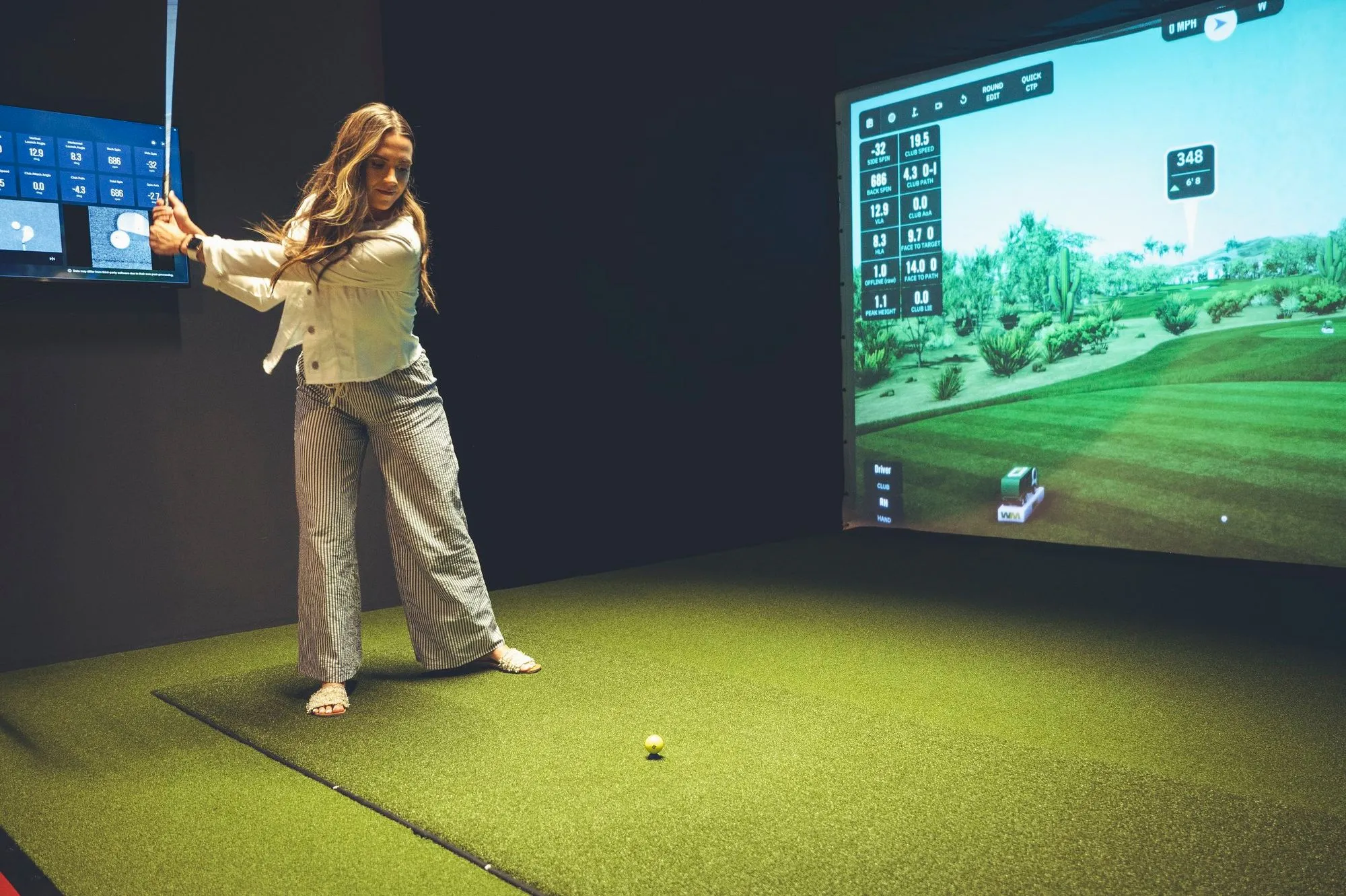 Guest taking a golf swing on the simulator with live shot data at The PAR Club