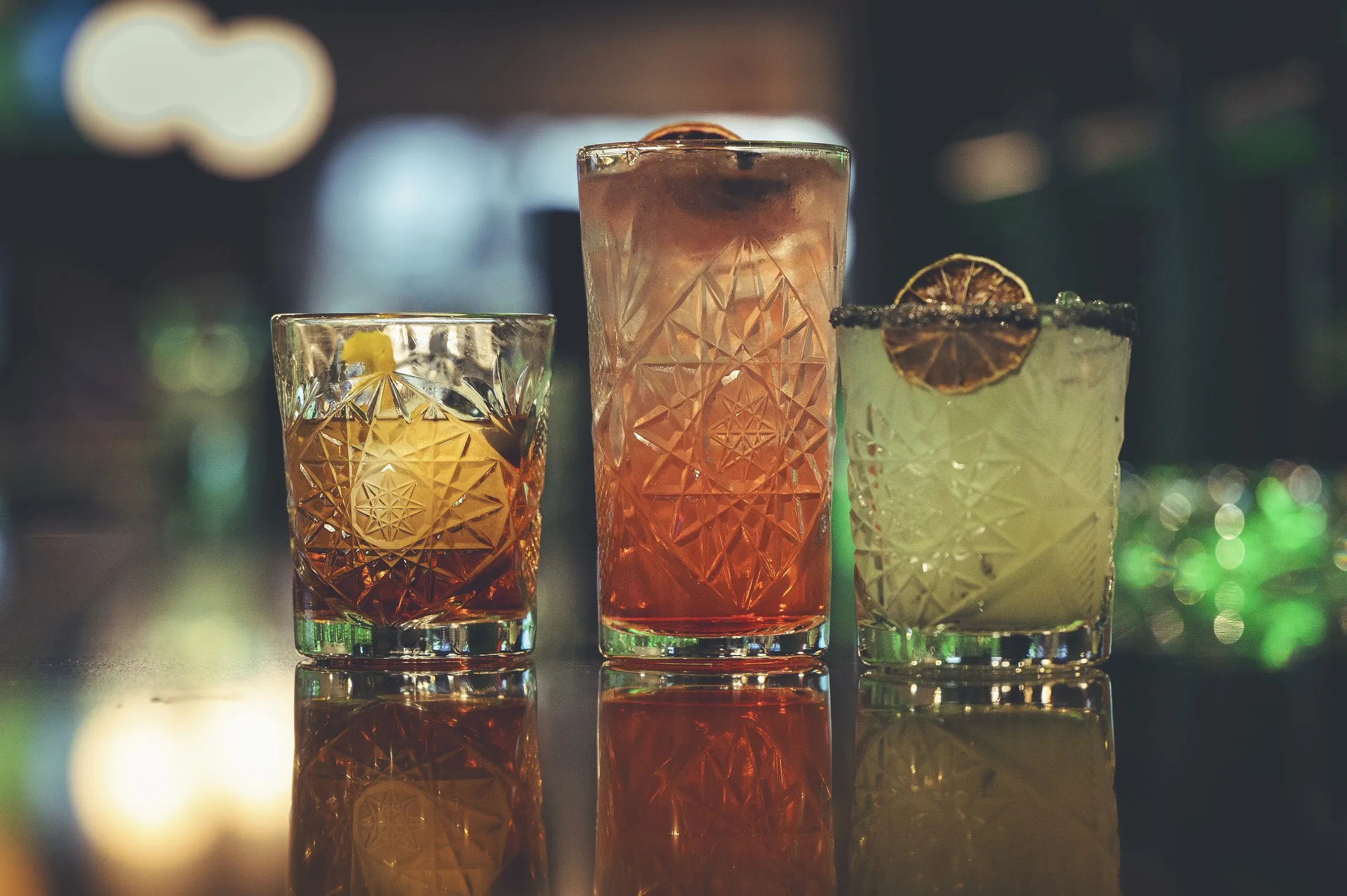 Three different craft cocktails lined up on the bar at The PAR Club