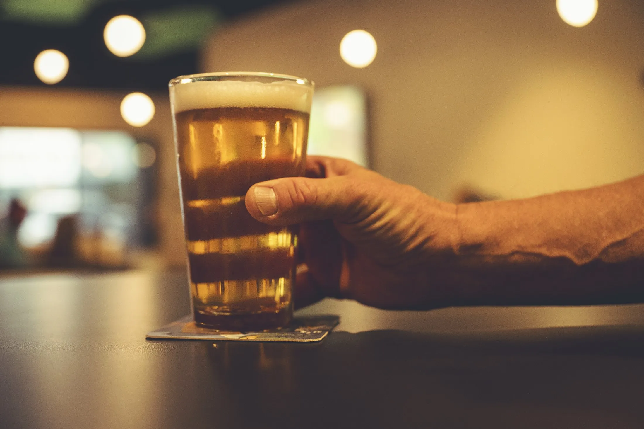 Hand holding a glass of draft beer at The PAR Club