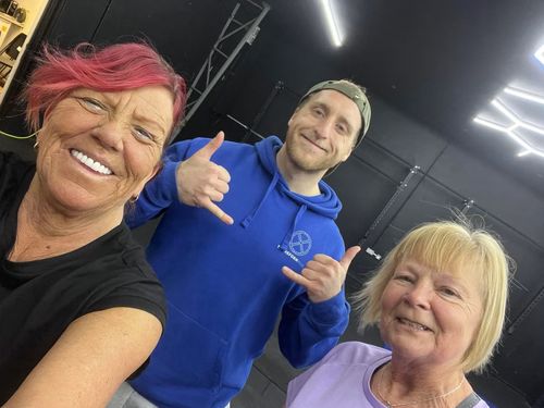 Women over 50 in our gym, smiling with one of our coaches