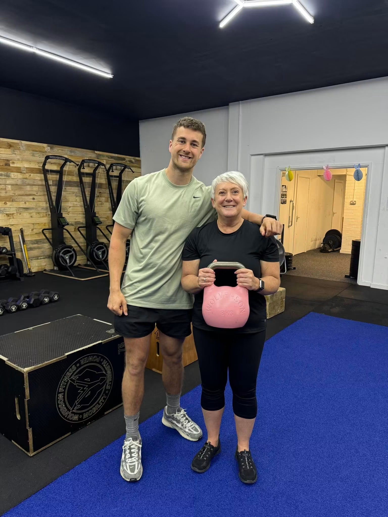 Older lady smiling in the gym with coach