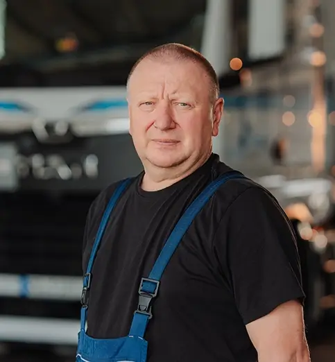Jürgen Lauterbach steht im dunklen T-Shirt vor einem LKW der Spedition Schott.
