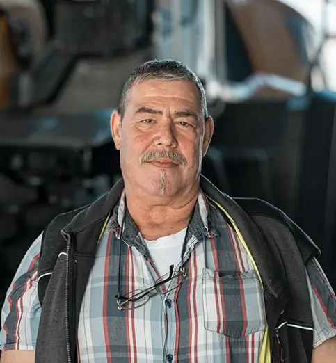 Harald Wolf steht in eine kariertem Hemd vor einem Radlader.
