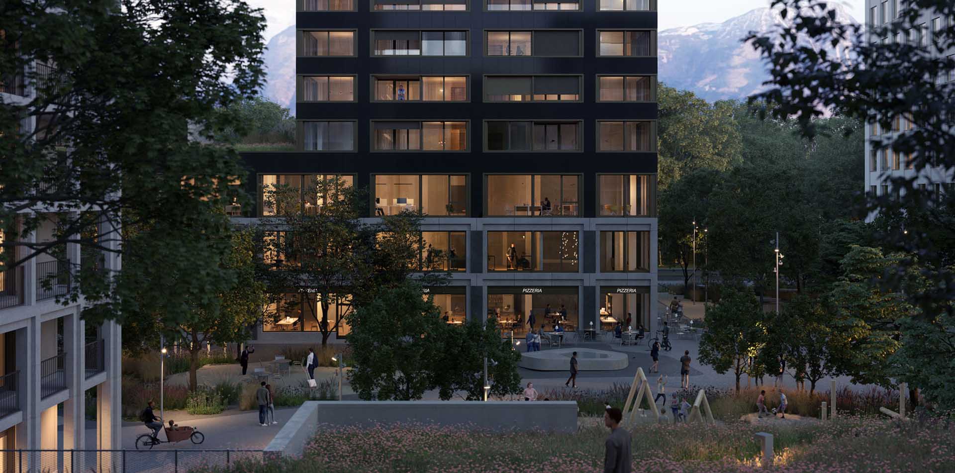 Evening scene of a modern residential building with lit windows, a pizzeria on the ground floor, outdoor seating, and people walking, cycling, and socializing in a landscaped courtyard with trees and playground equipment, set against a backdrop of mountains.
