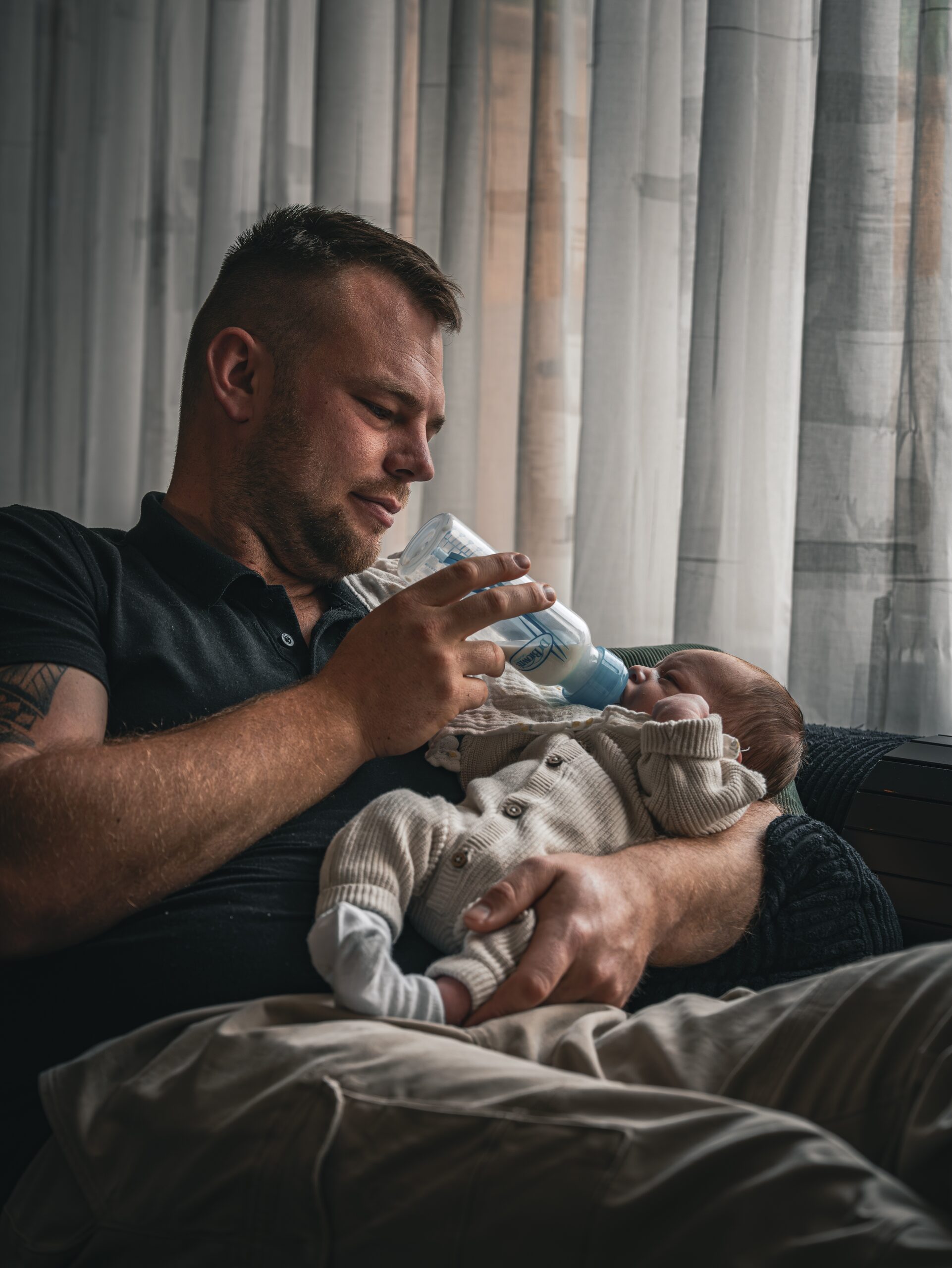 Vader geeft de pasgeboren baby de fles tijdens een rustige newbornreportage