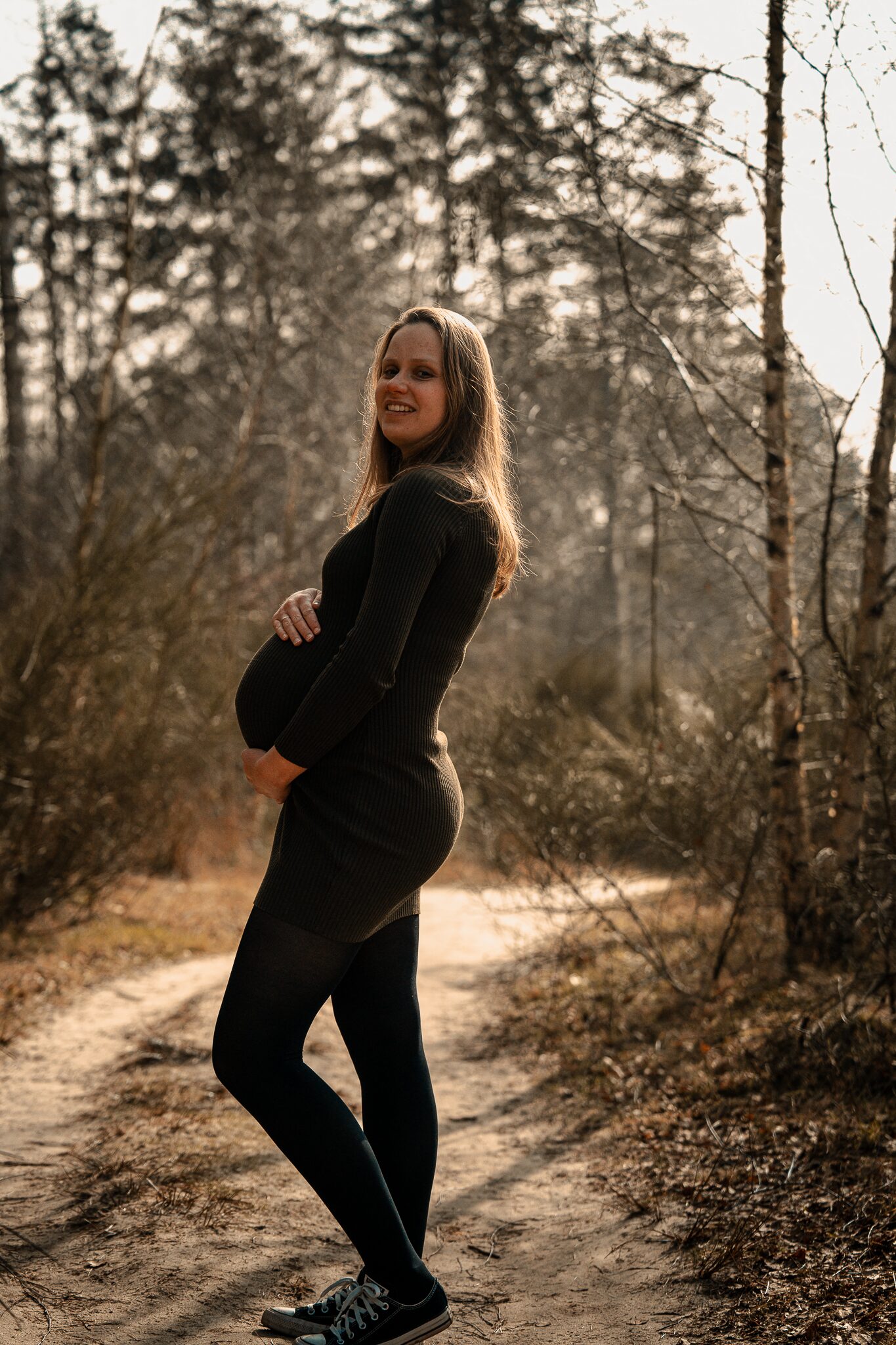 Zwangere vrouw in warm avondlicht tijdens een zwangerschapsshoot in Drenthe