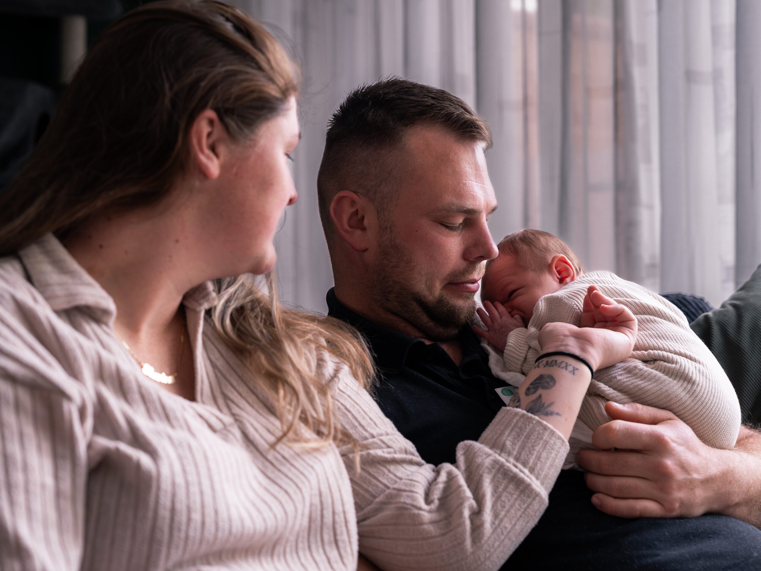 Ouders met hun pasgeboren baby tijdens een ontspannen newbornshoot thuis