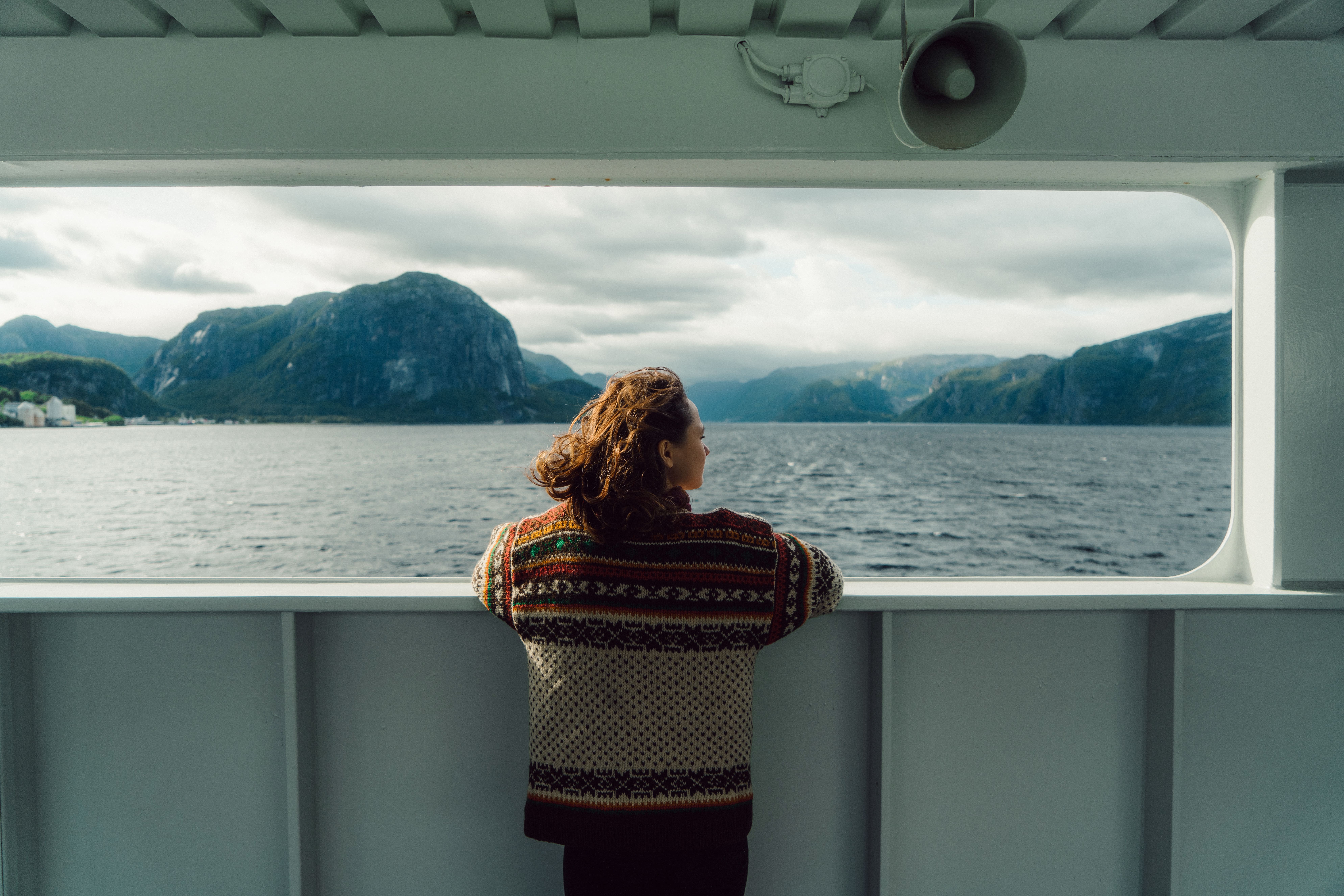 Person gazing over Norwegian fjord from ship, symbolizing HELINOR Energy’s vision for a sustainable, zero-emission maritime future