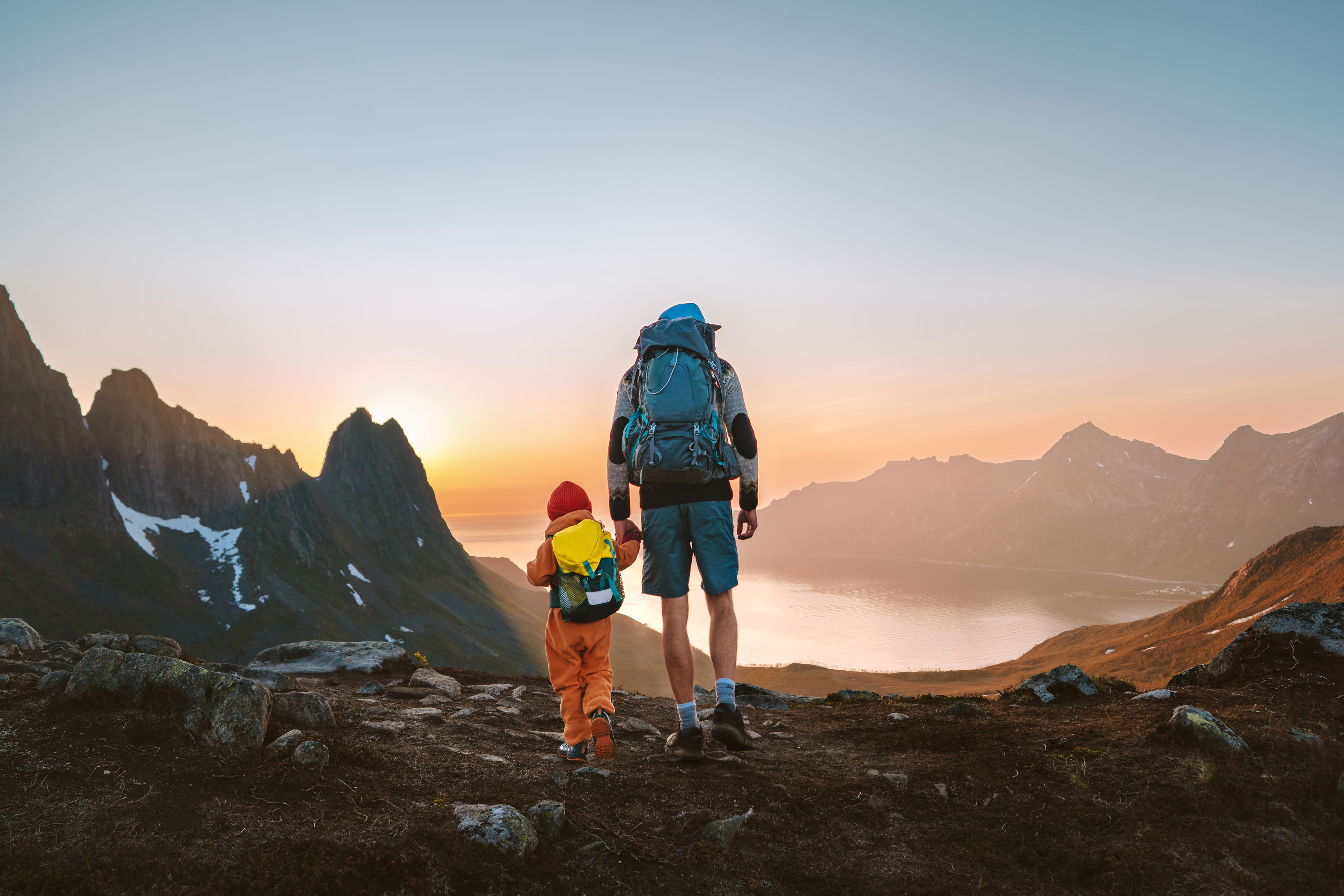 Adult and child hiking in the Norwegian mountains at sunrise, symbolizing HELINOR Energy’s commitment to a clean, sustainable future for the next generation