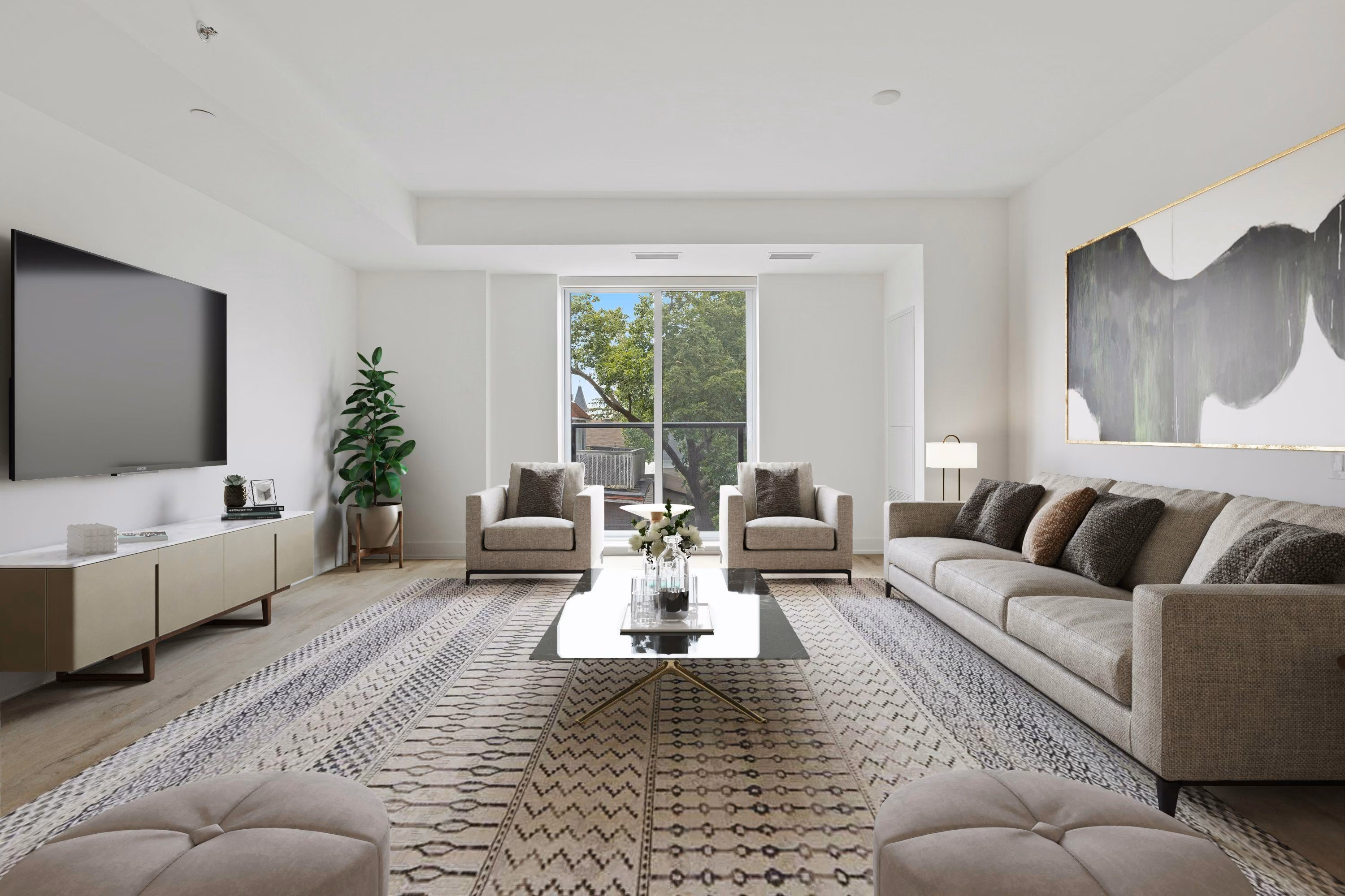 Modern living room with a large beige sofa, two armchairs, a patterned area rug, a low coffee table with flowers, a flat-screen TV on the wall, and a large abstract painting.