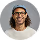 Smiling man wearing glasses and a dark cap with long curly hair.