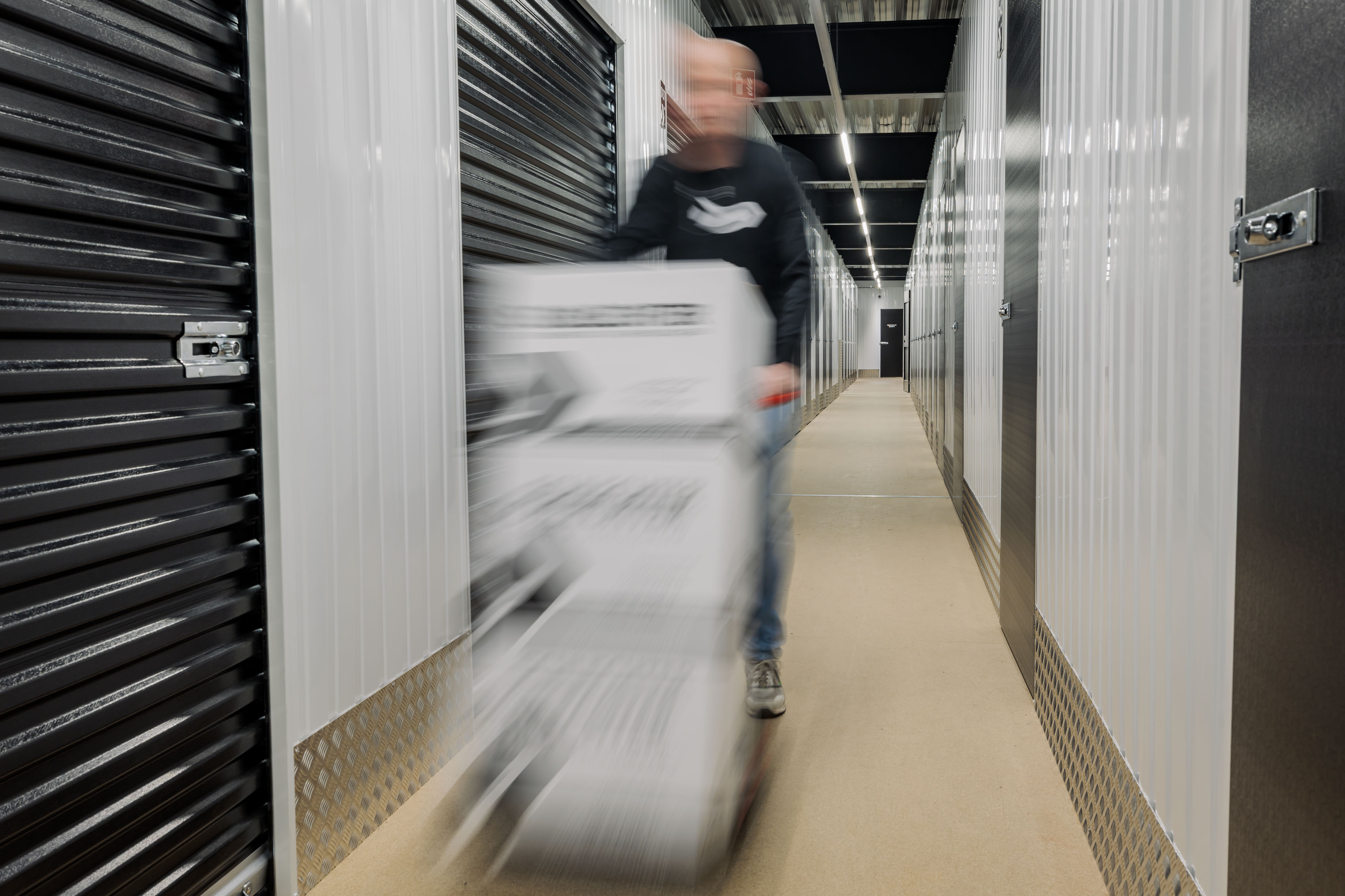 Medewerker rijdt met een steekwagen vol dozen door de gang van Schlechter Selfstorage